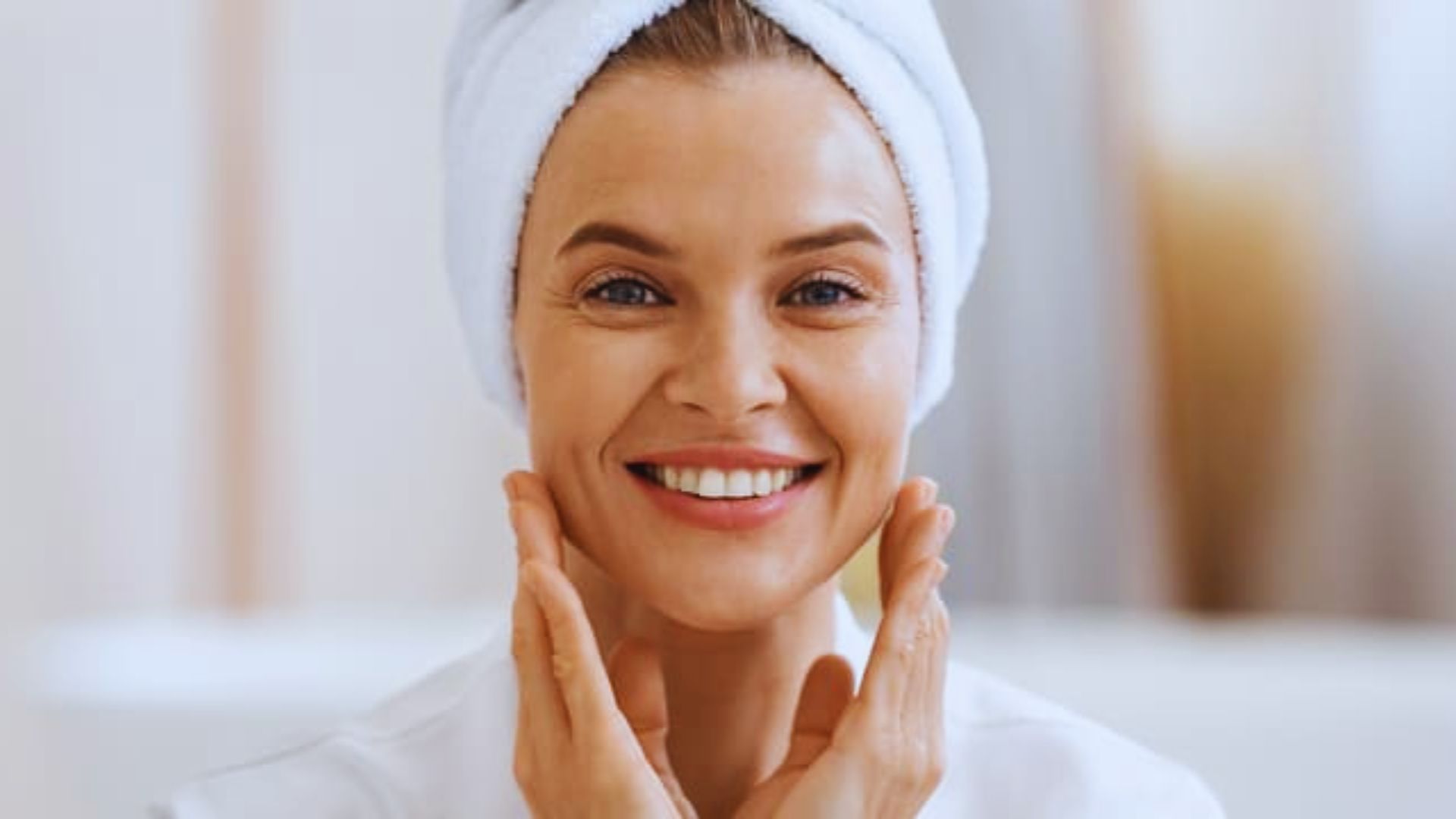 A smiling woman with a towel wrapped around her head, exuding a sense of joy and relaxation.