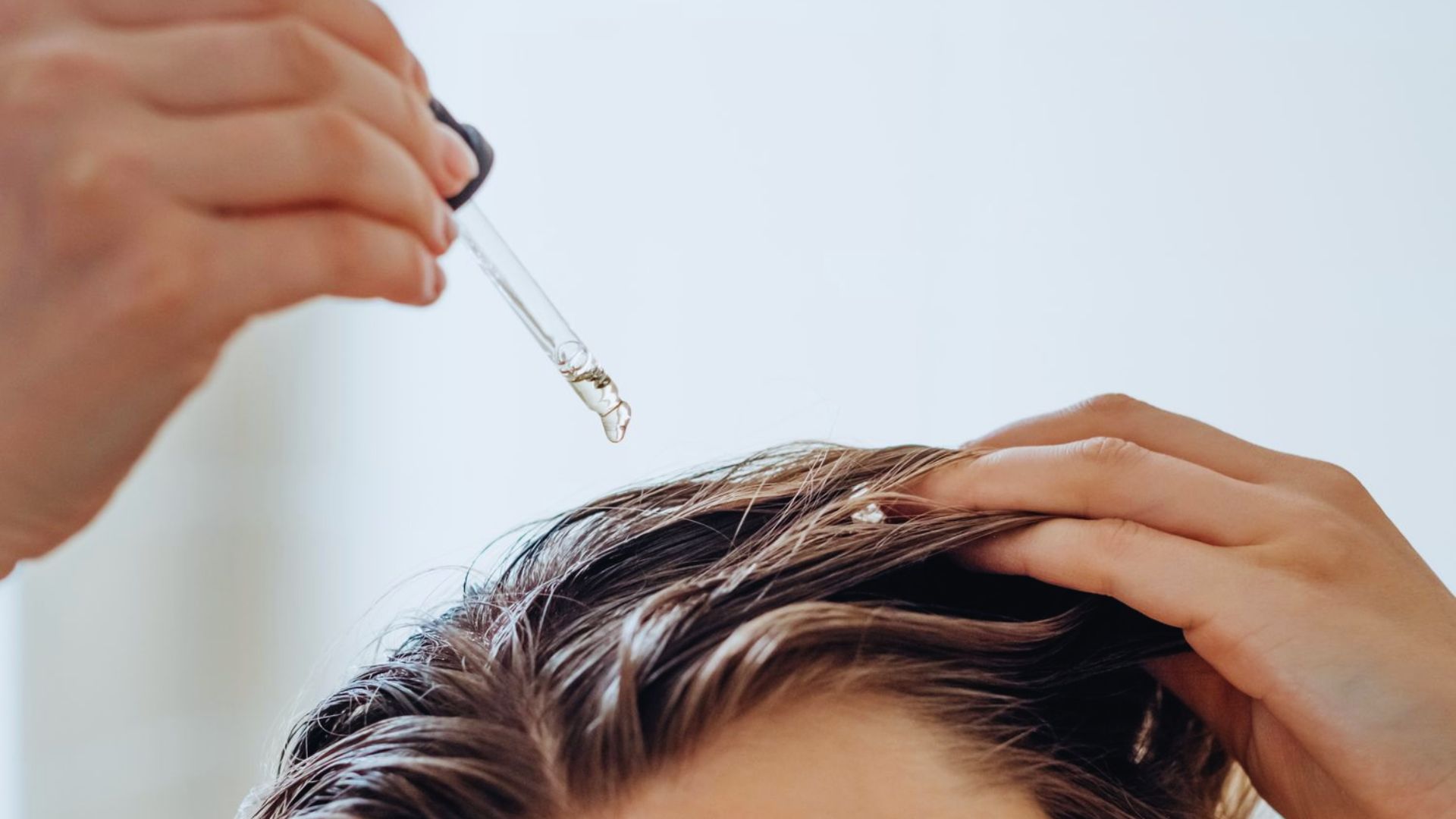A person having their hair washed while a hair dryer is used to dry it.