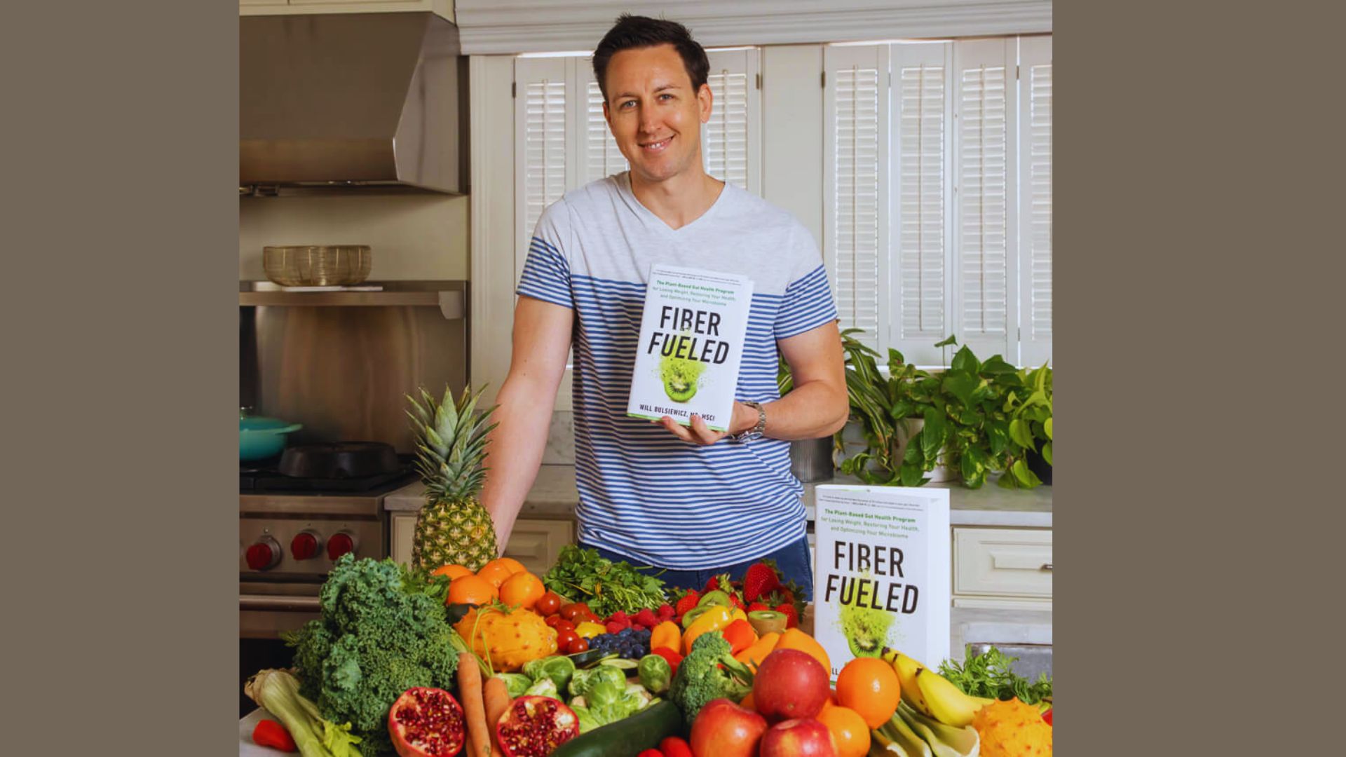 A man holds a book featuring an illustration of various vegetables on the cover.