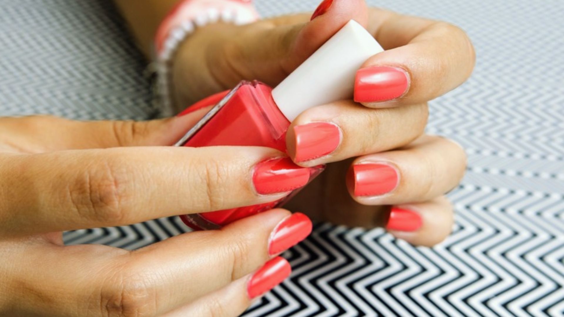 A close-up of a woman's hands showcasing red and white nail polish on her fingernails.