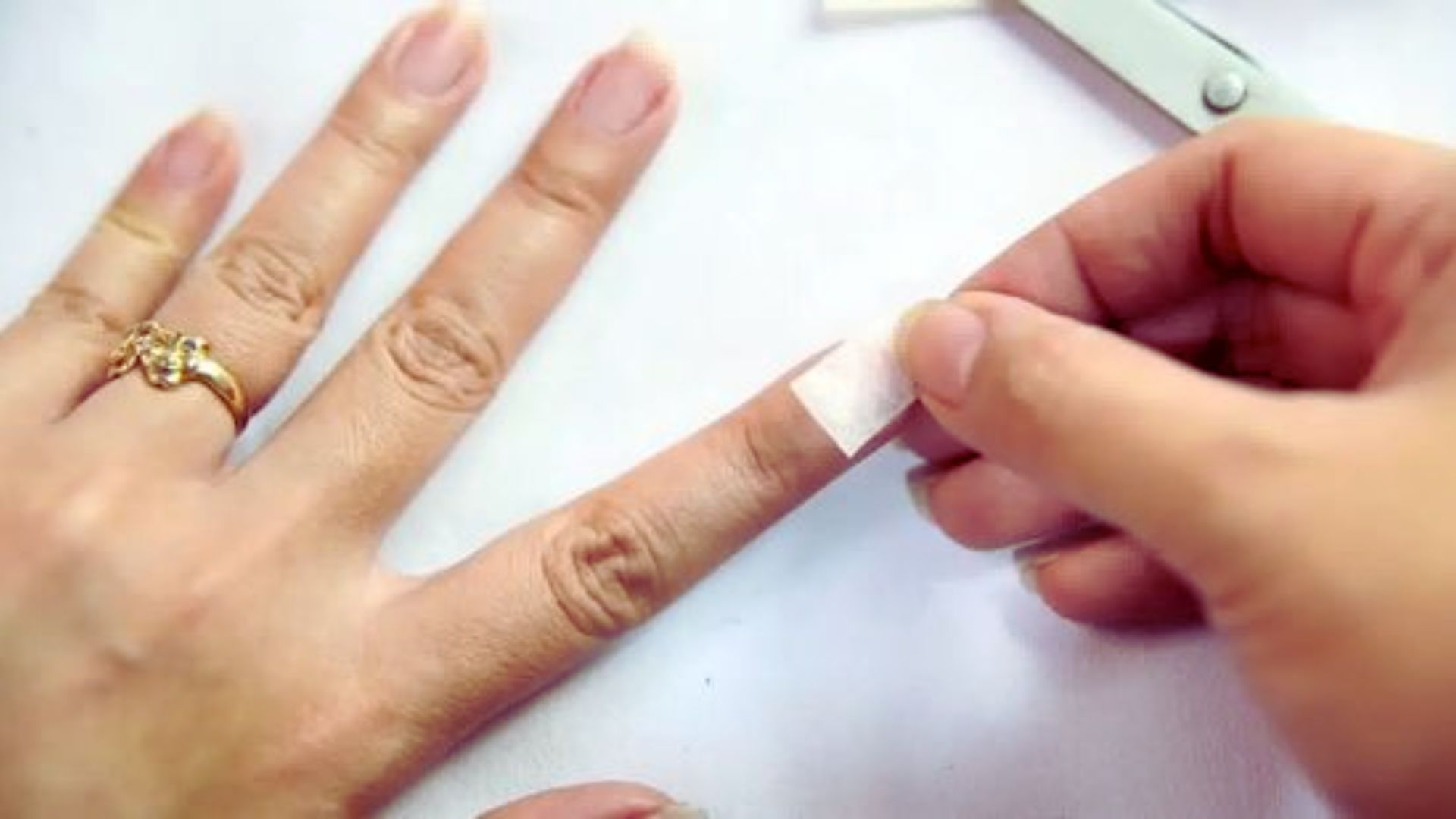 A person holding a nail file next to a freshly manicured nail, demonstrating nail care techniques.