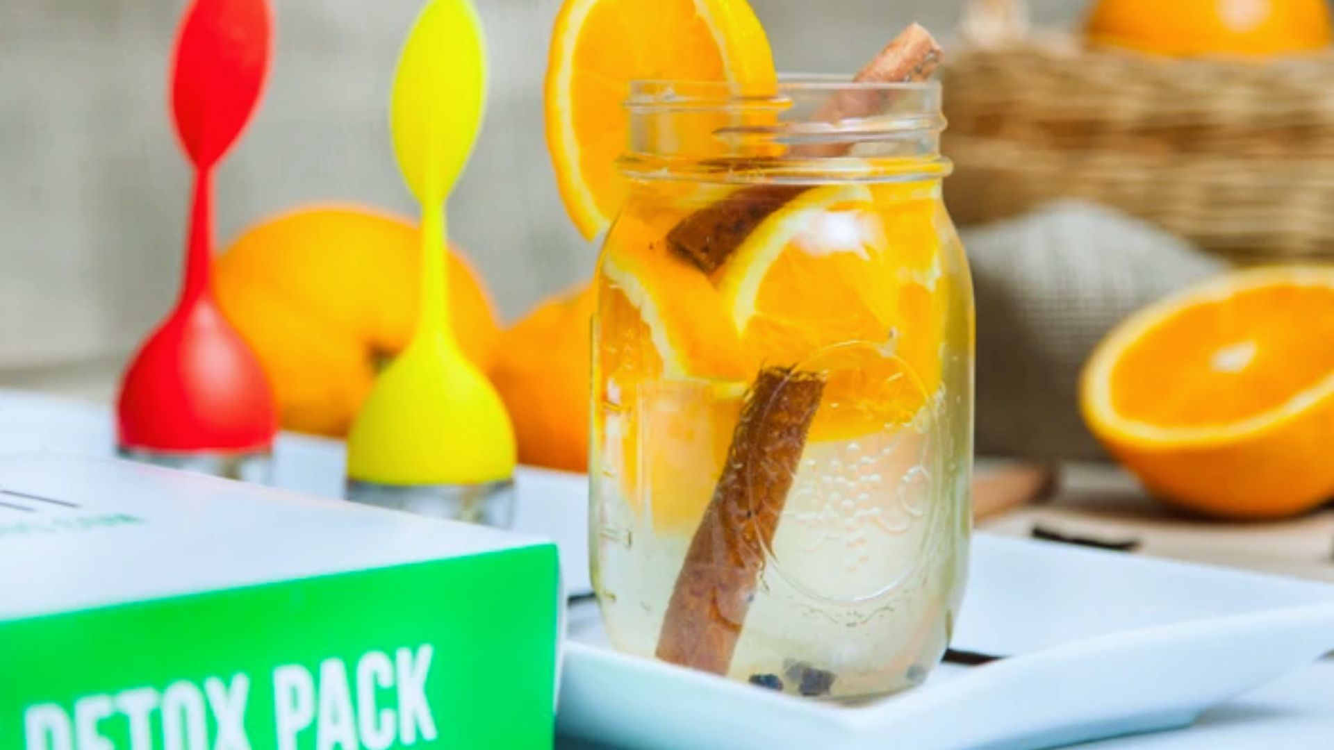 A jar of detox pack surrounded by fresh orange slices and cinnamon sticks, showcasing a vibrant and aromatic display.