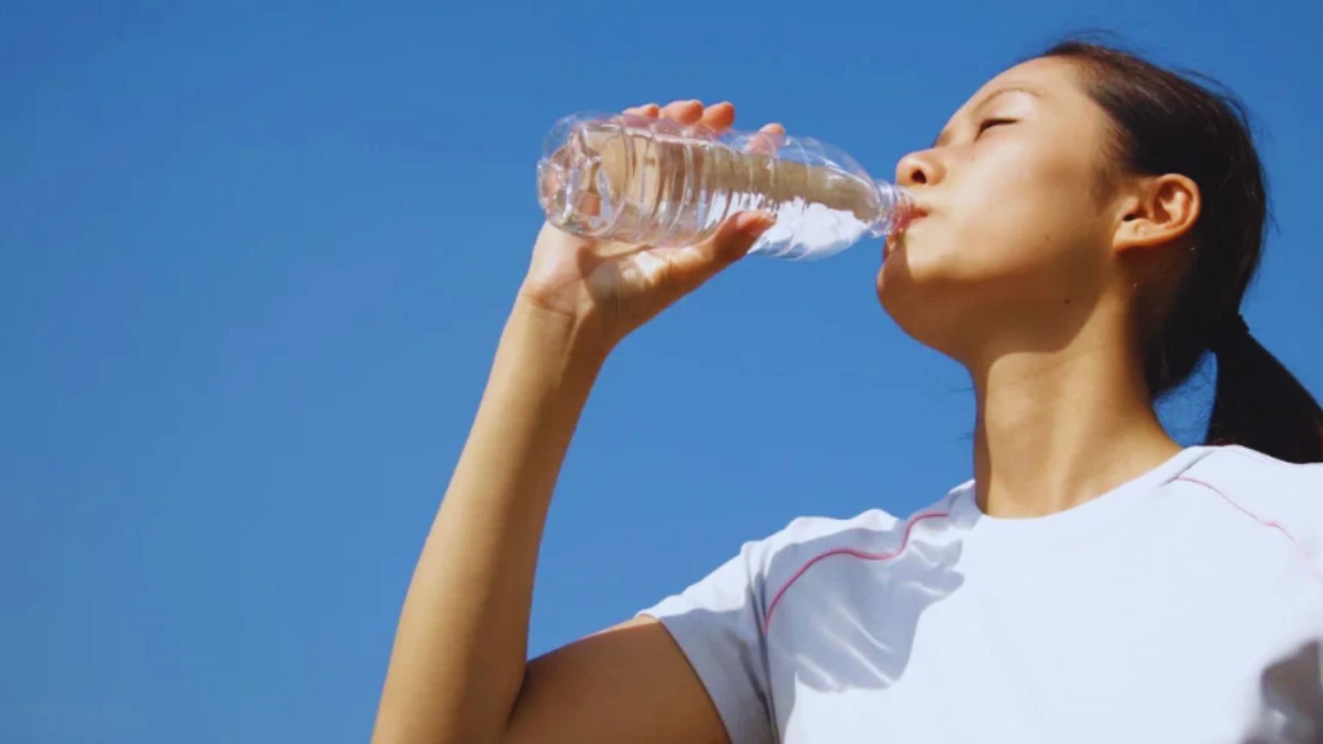 A woman takes a sip from a water bottle, staying hydrated during her activity.