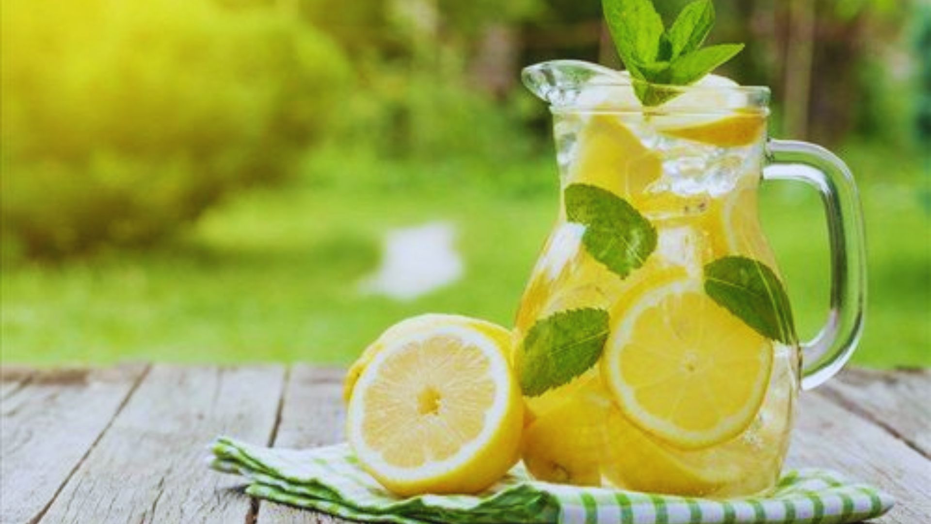 A pitcher of lemonade sits on a table covered with a green cloth, inviting and refreshing in appearance.