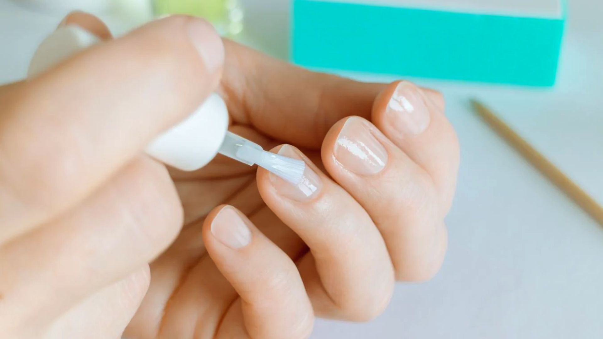 A person applying nail polish remover to their nails to remove the existing nail polish.