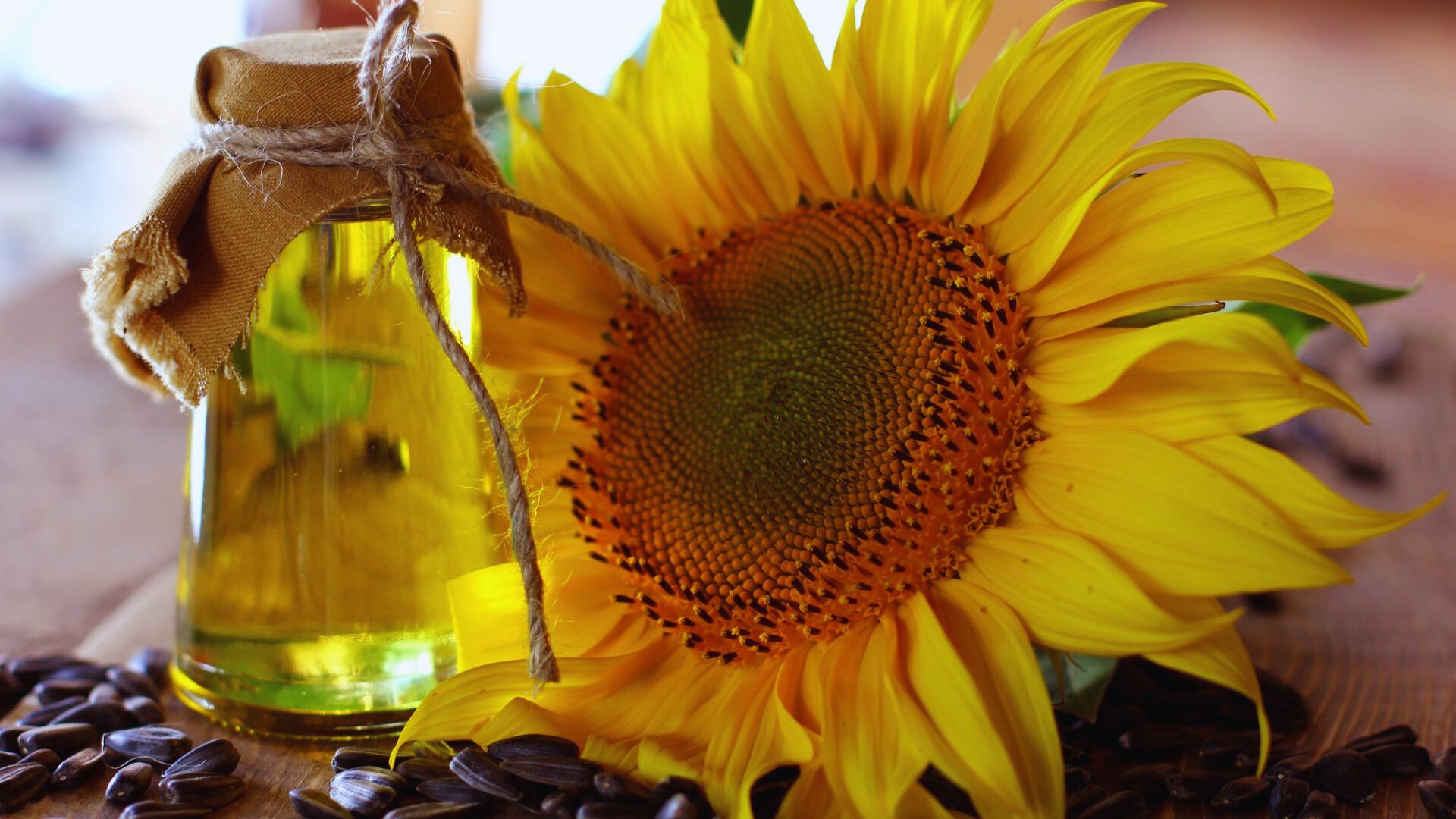A bottle of sunflower oil beside a pile of roasted coffee beans on a wooden surface.