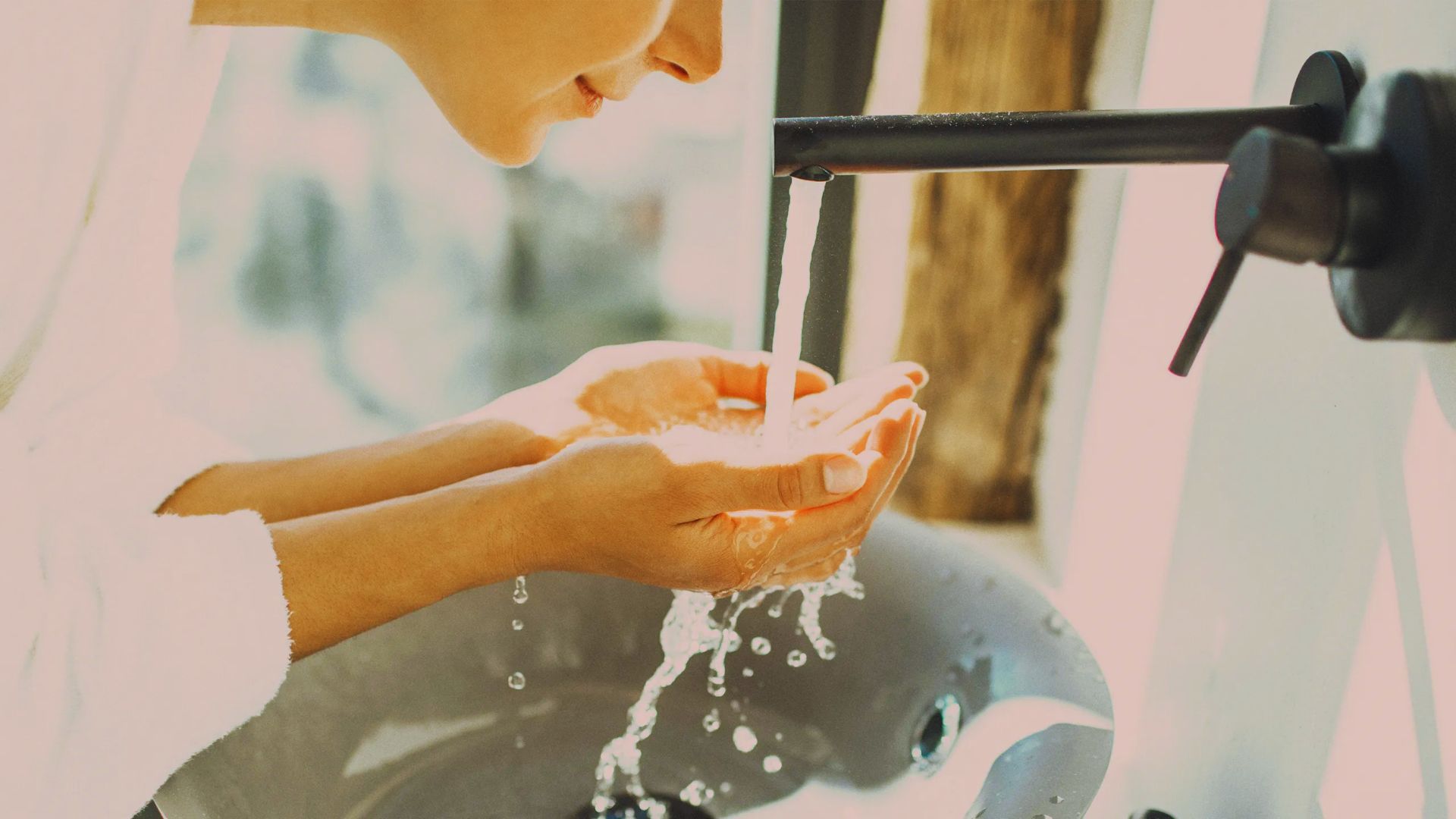 A woman washing her hands under running water at a sink, promoting hygiene and cleanliness.