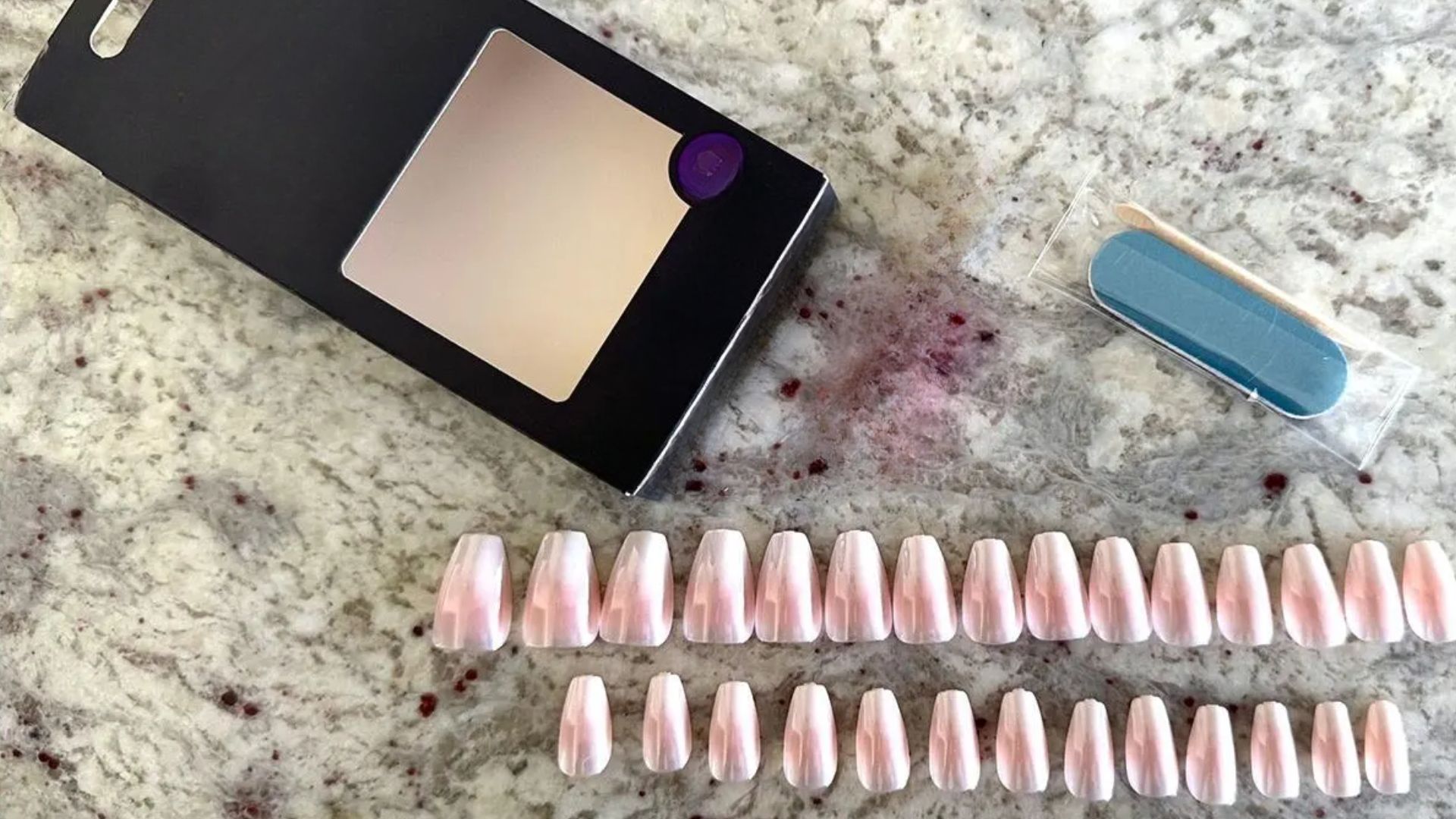 A box of colorful nail polish next to a pair of elegant nail extensions on a white background.