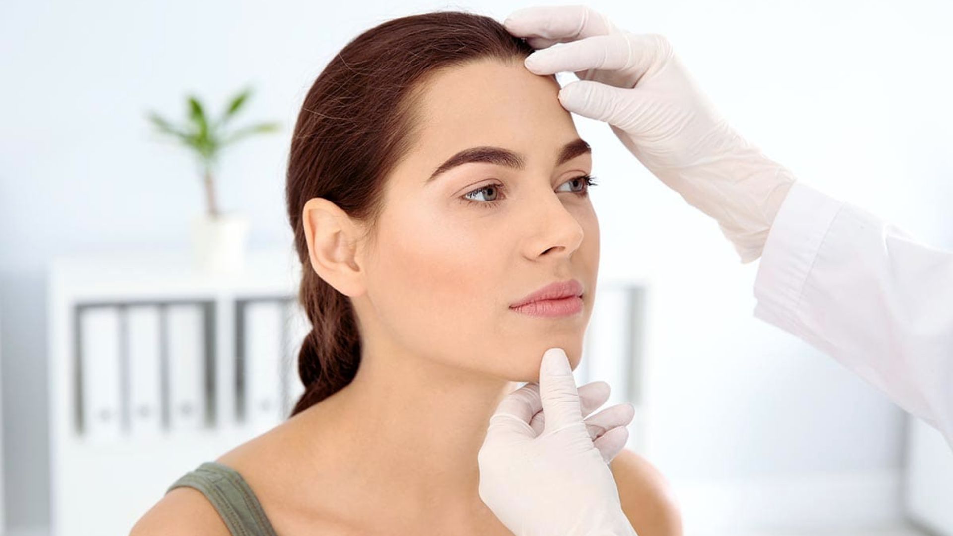 A woman being evaluated by a doctor during a facial check-up in a medical office.
