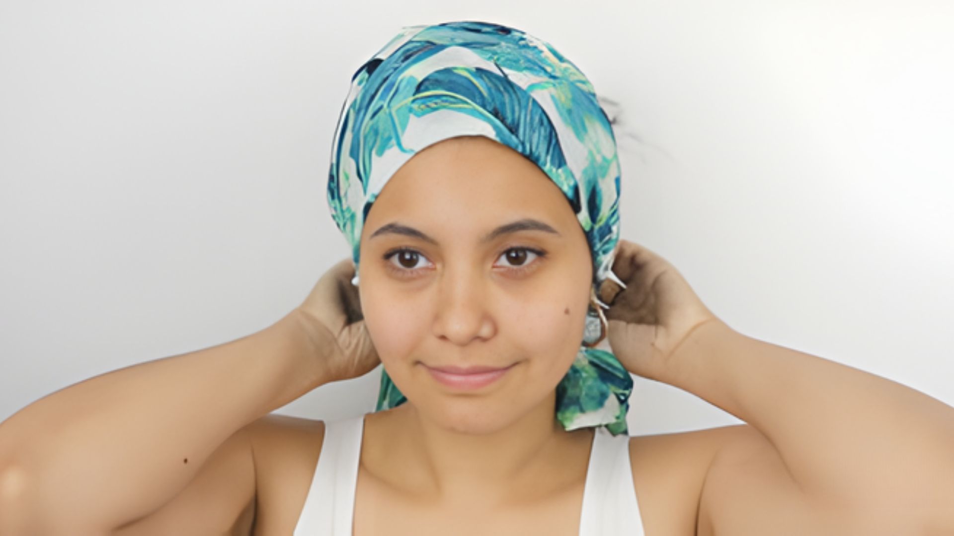A woman in a turban gently holds her hair, showcasing a blend of cultural style and personal expression.