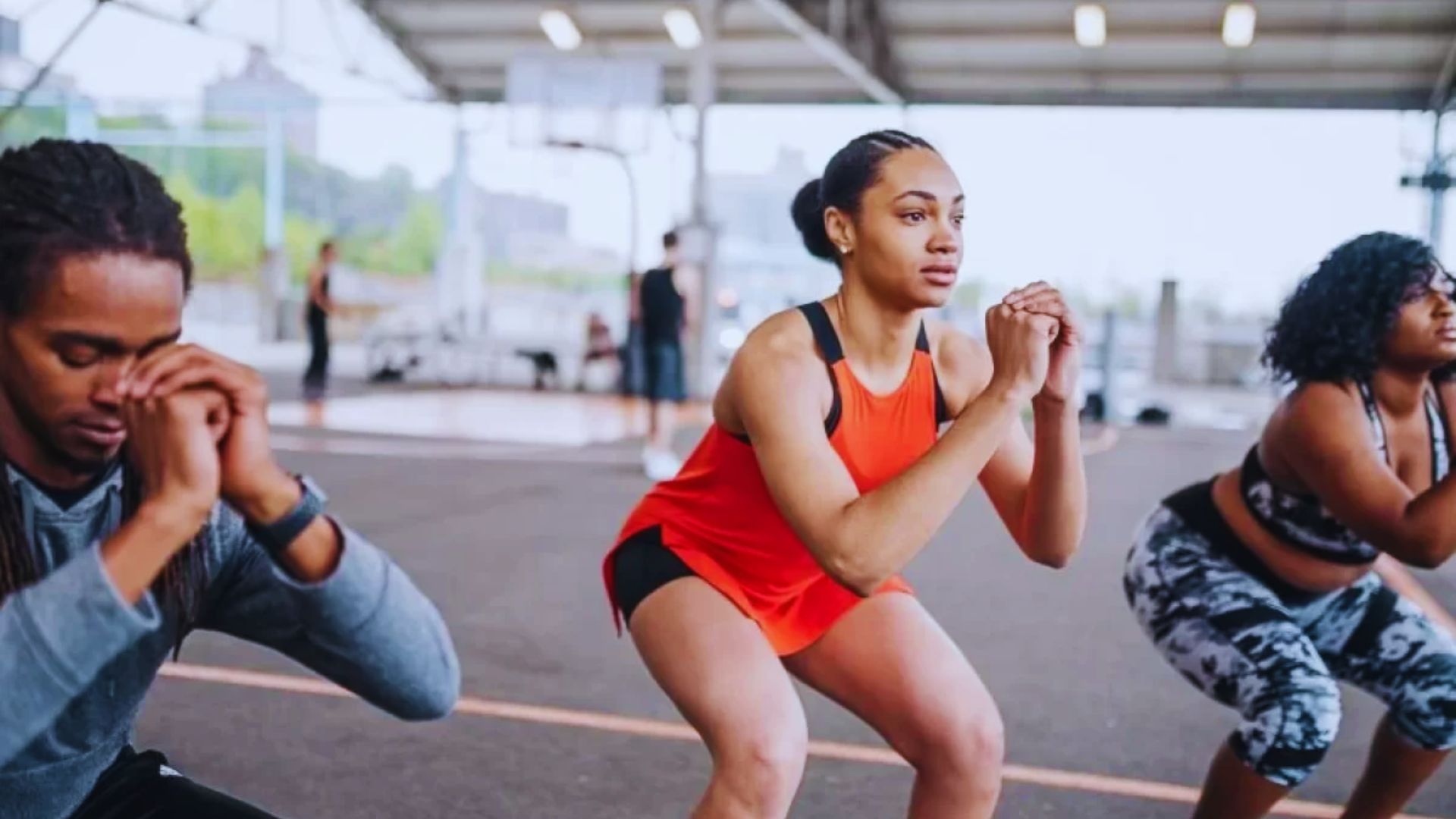 A group of individuals performing squats together in a well-lit indoor gym setting.