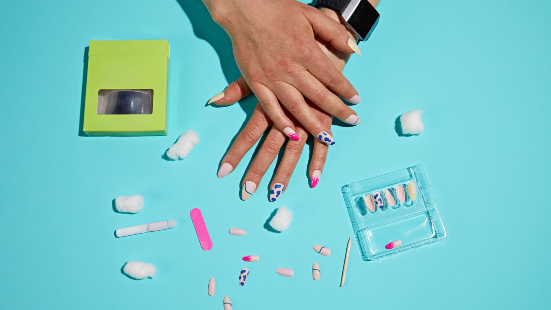 A woman's hands hold a colorful nail polish kit, showcasing various shades and tools for nail art.
