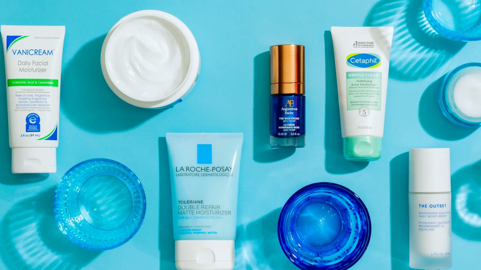 A selection of skin care products arranged on a blue surface, showcasing various bottles and containers.