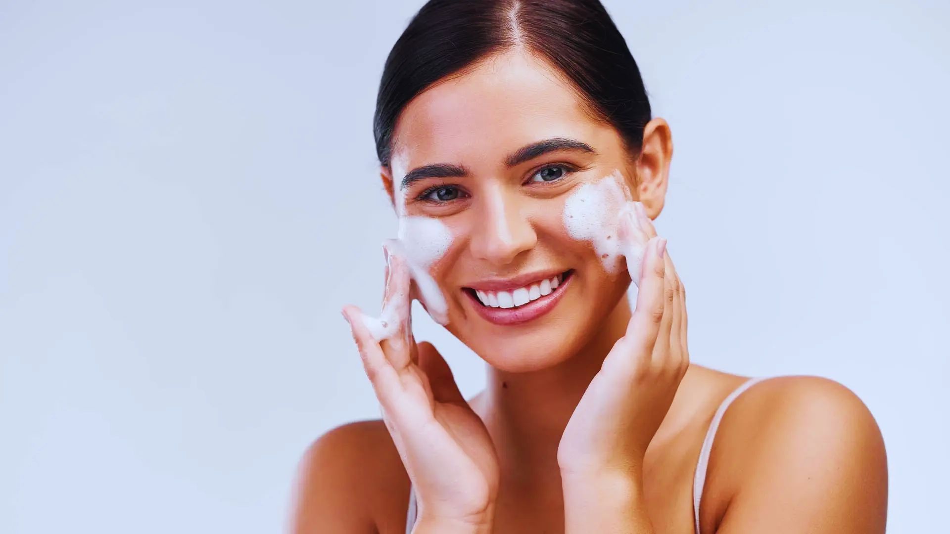 A smiling woman holds a face mask, conveying a sense of positivity and health awareness.