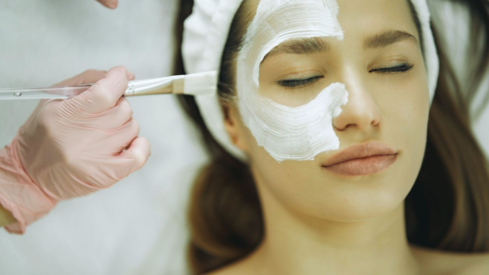 A woman receiving a facial treatment while wearing a soothing mask, relaxing in a spa environment.