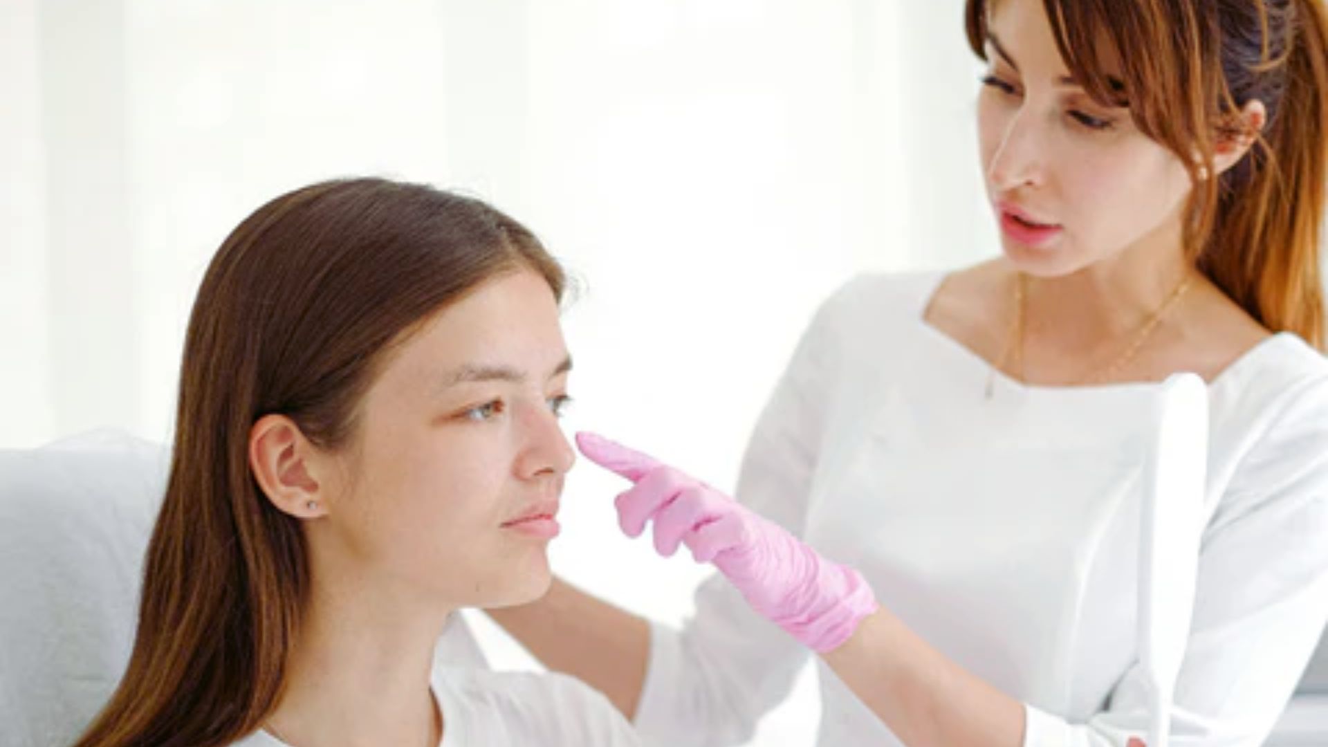 A doctor carefully shaping a woman's eyebrows during a cosmetic procedure.