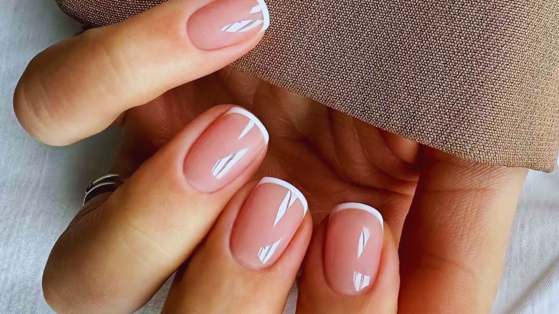 A woman's hand displaying a vibrant pink manicure against a neutral background.