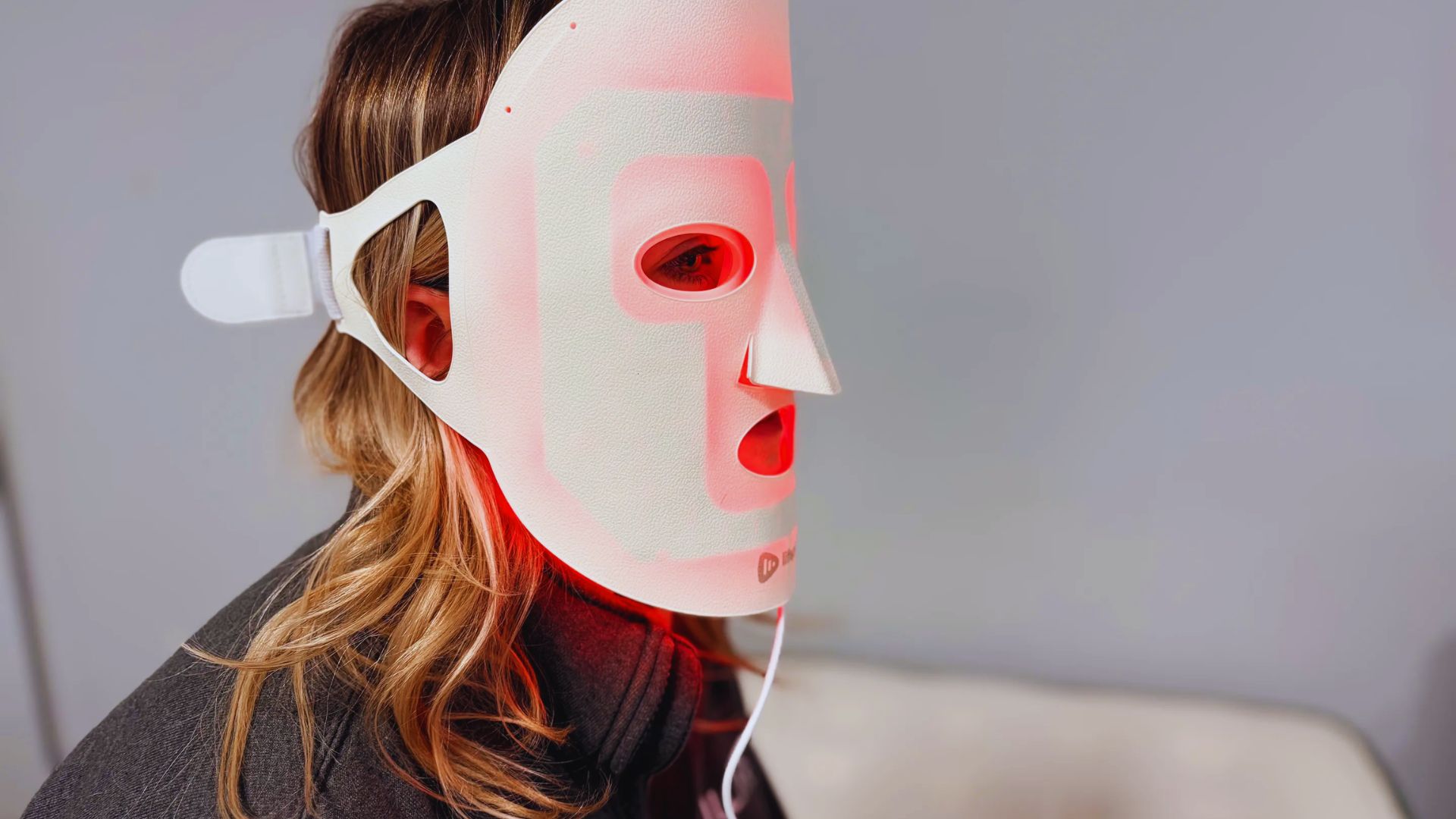 A woman wearing a red LED mask, showcasing a vibrant and futuristic design.