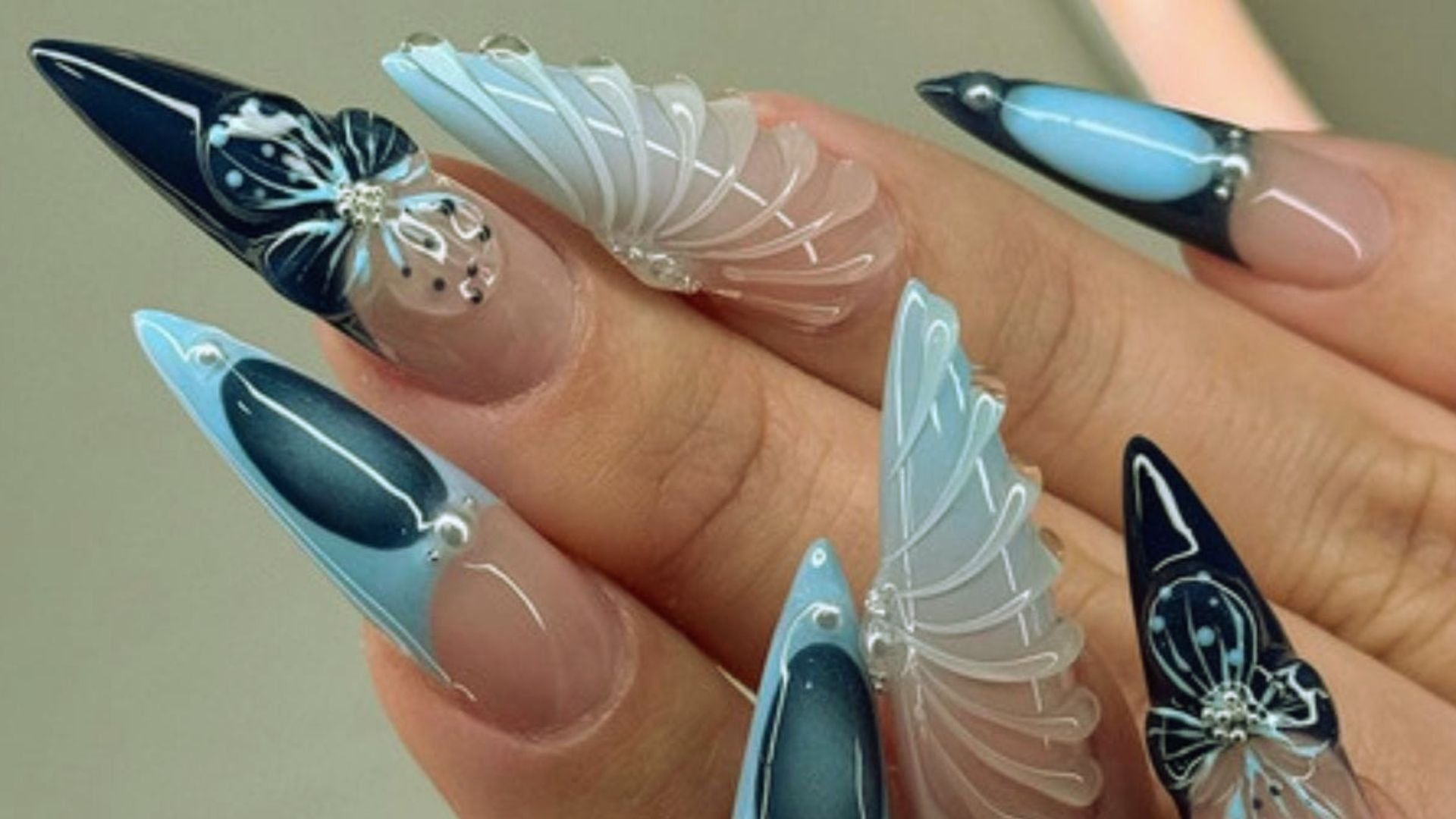 A close-up of a woman's nails featuring intricate blue and white designs.