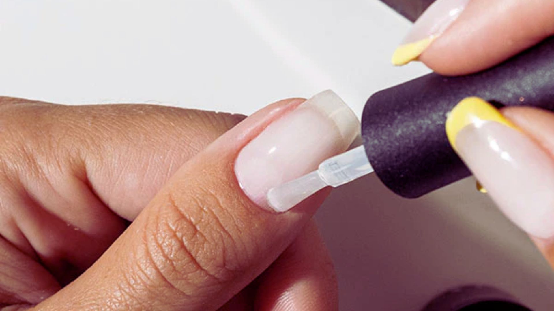 A person applies nail polish using a nail brush, focusing on precision and detail in their manicure.