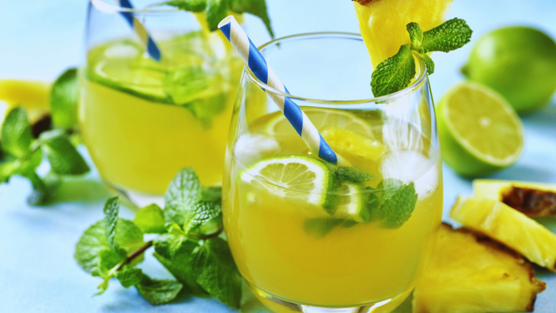 Two glasses of refreshing pineapple and lime juice garnished with fresh mint leaves.