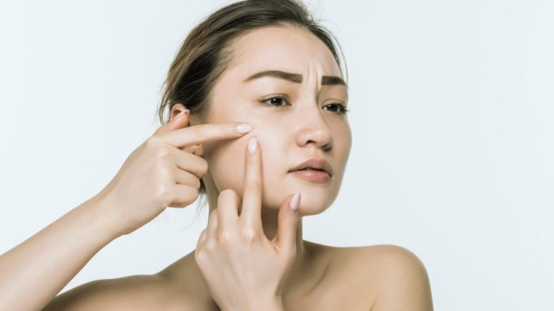 A woman gently touches her face with her fingers, conveying a moment of contemplation or self-reflection.