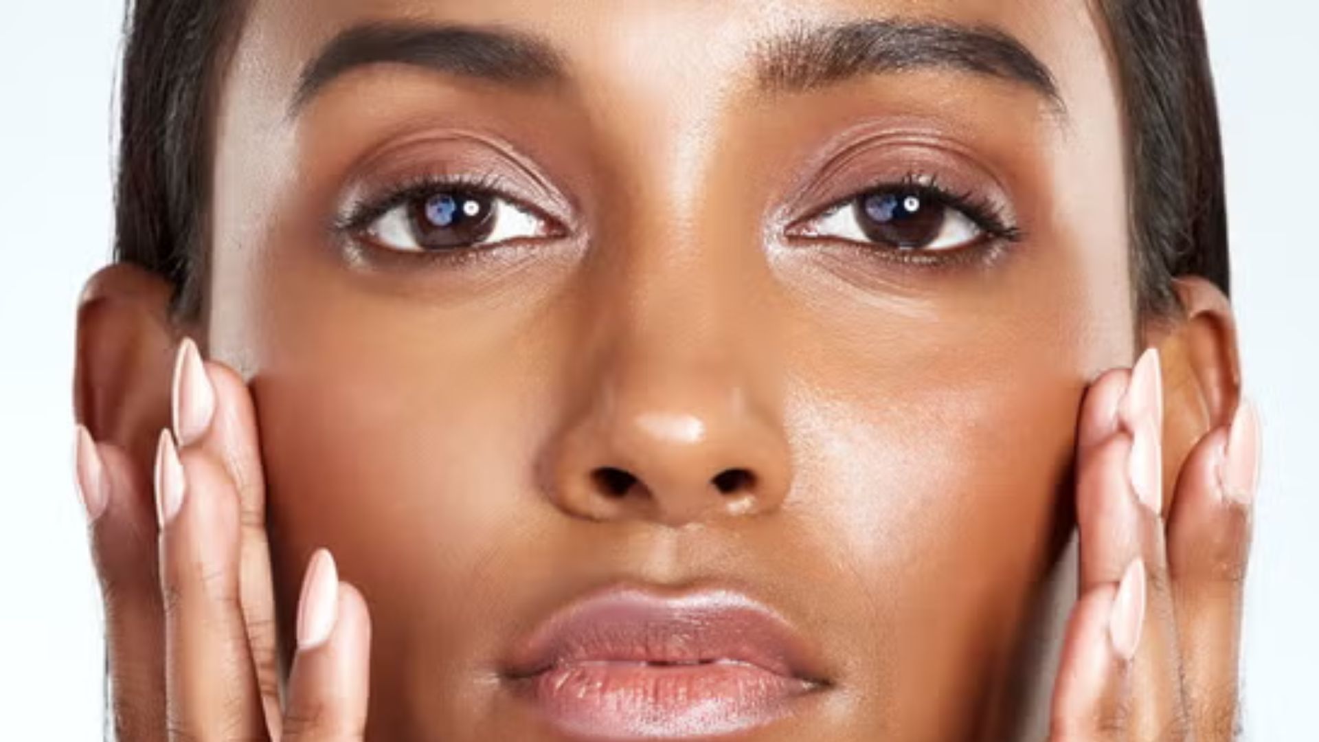 A woman with brown skin stands against a plain white background, showcasing her features and expression.
