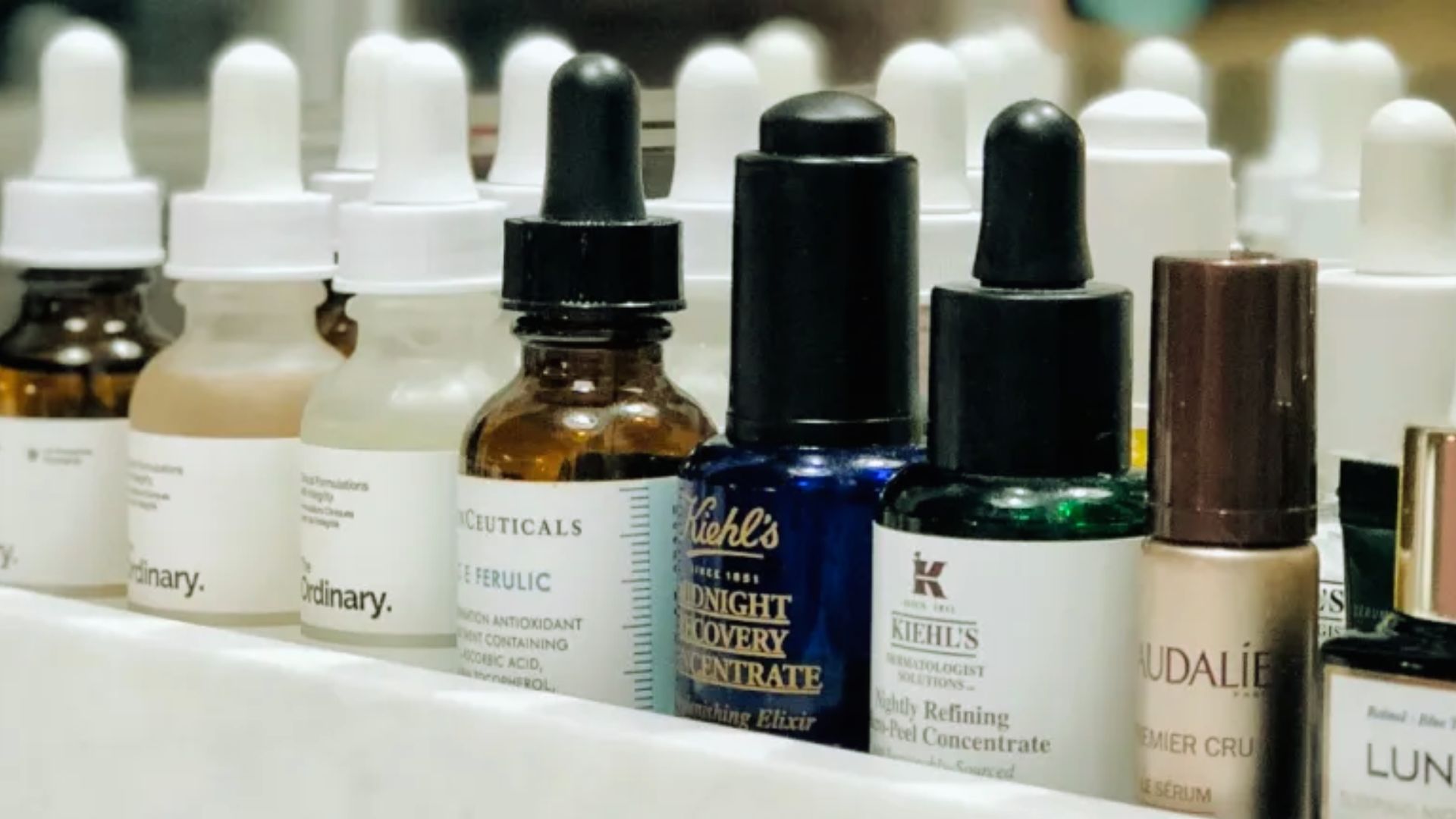 A row of various skincare product bottles neatly arranged on a countertop.