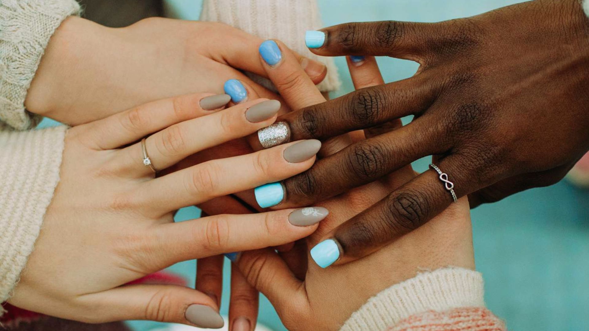 A diverse group of people showcasing a variety of colorful nail designs and polish shades.