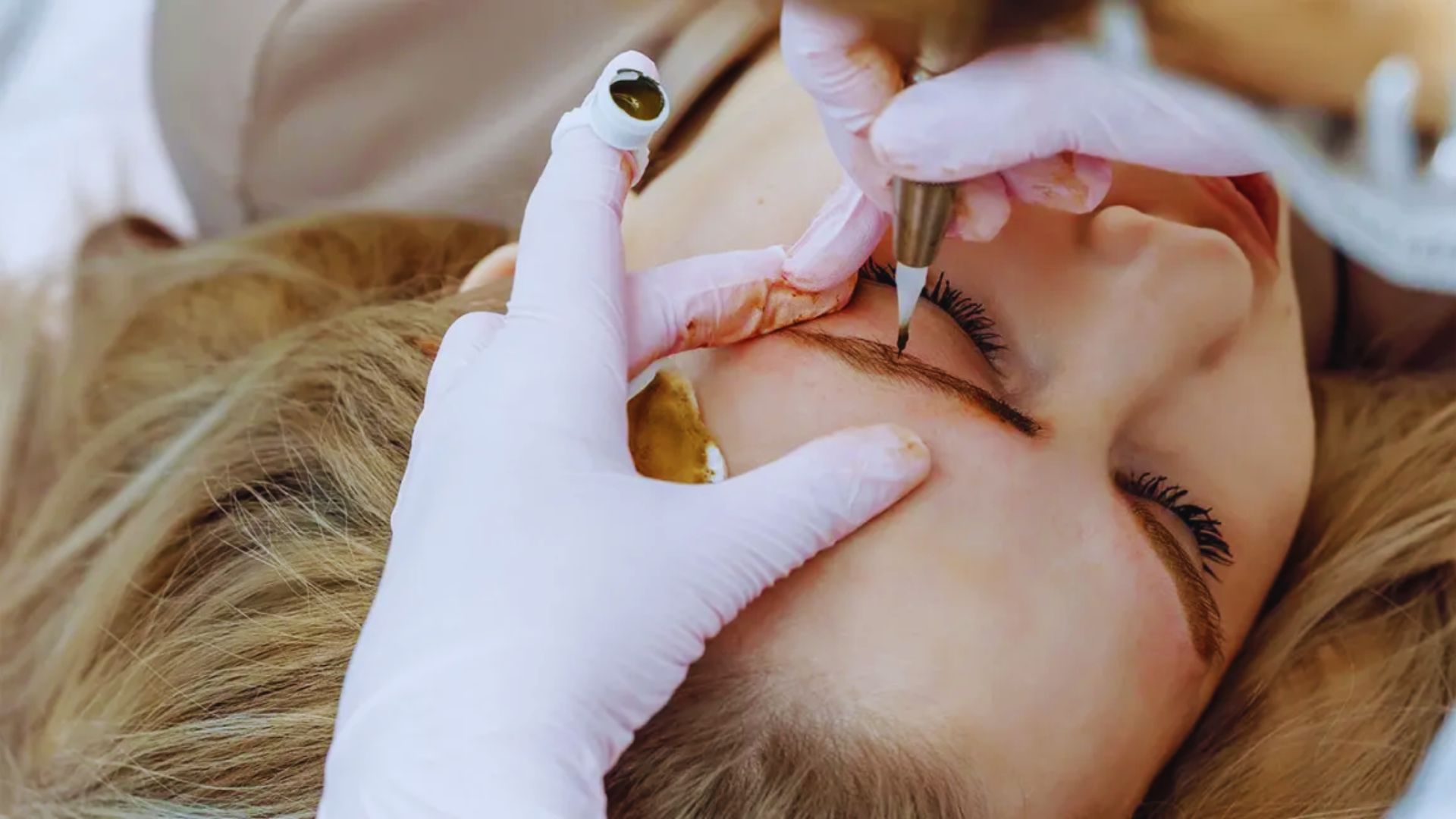 A doctor carefully shaping a woman's eyebrows during a cosmetic procedure.