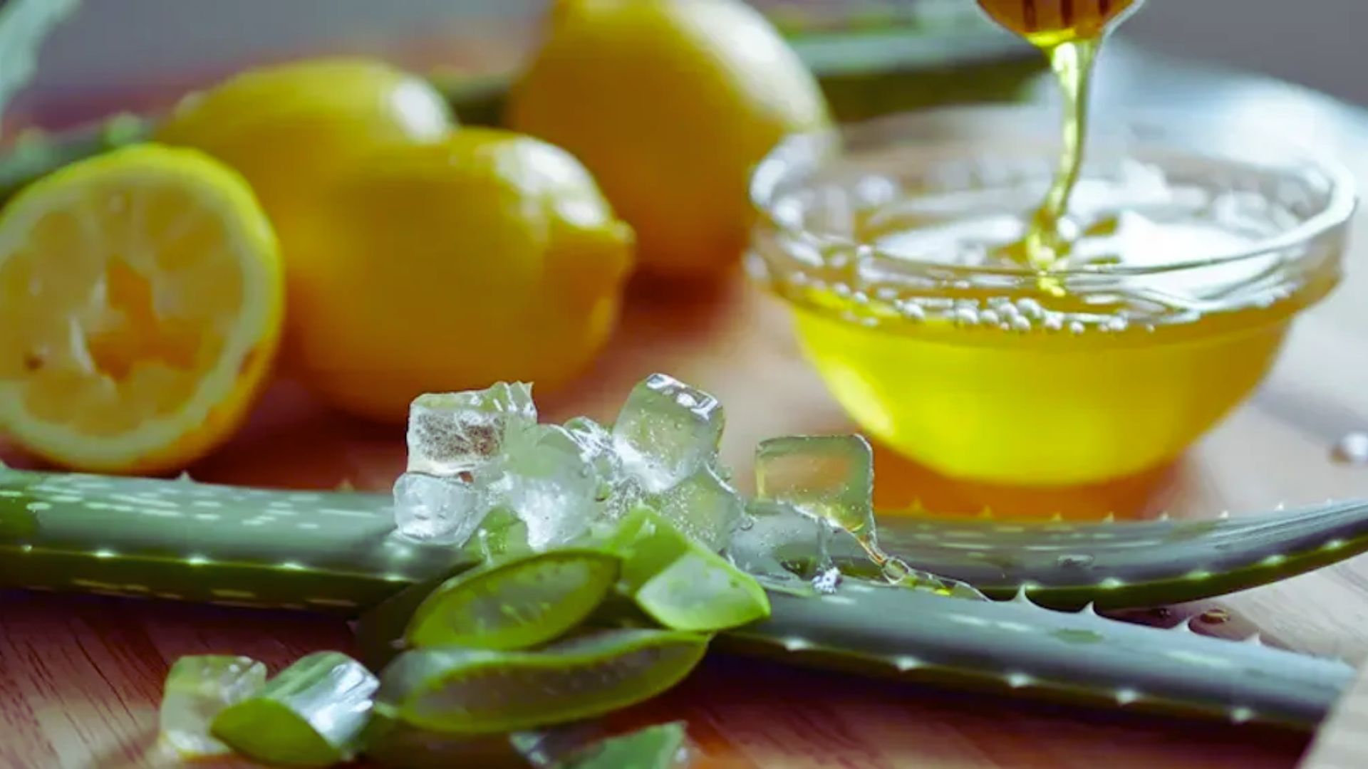 Aloe vera juice is being poured over fresh lemon slices, creating a refreshing and vibrant drink presentation.