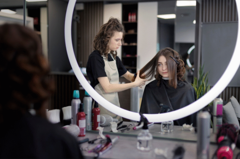 A woman sits in a salon chair as a stylist cuts her hair.