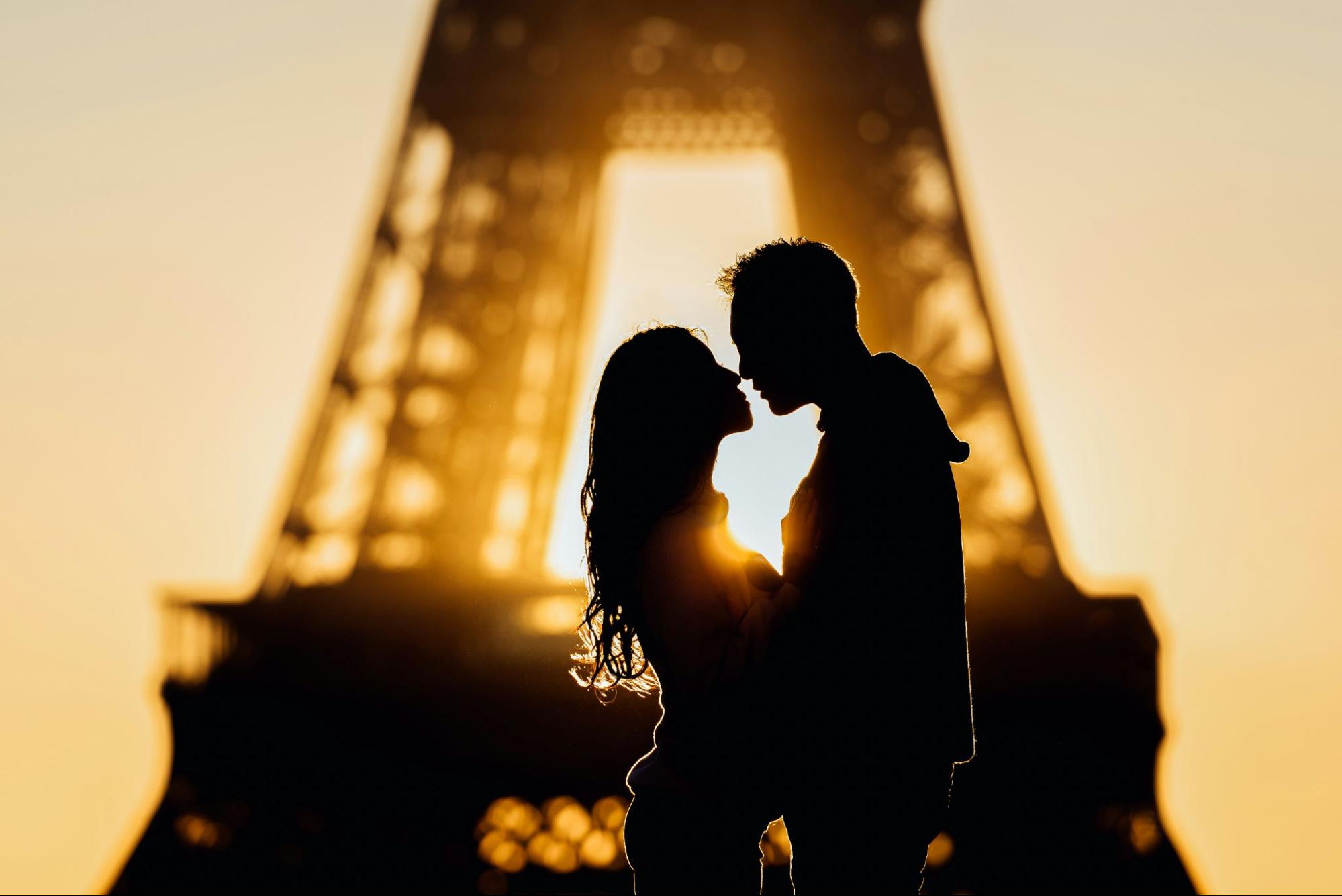 A couple shares a romantic kiss in front of the Eiffel Tower, capturing a moment of love in Paris.