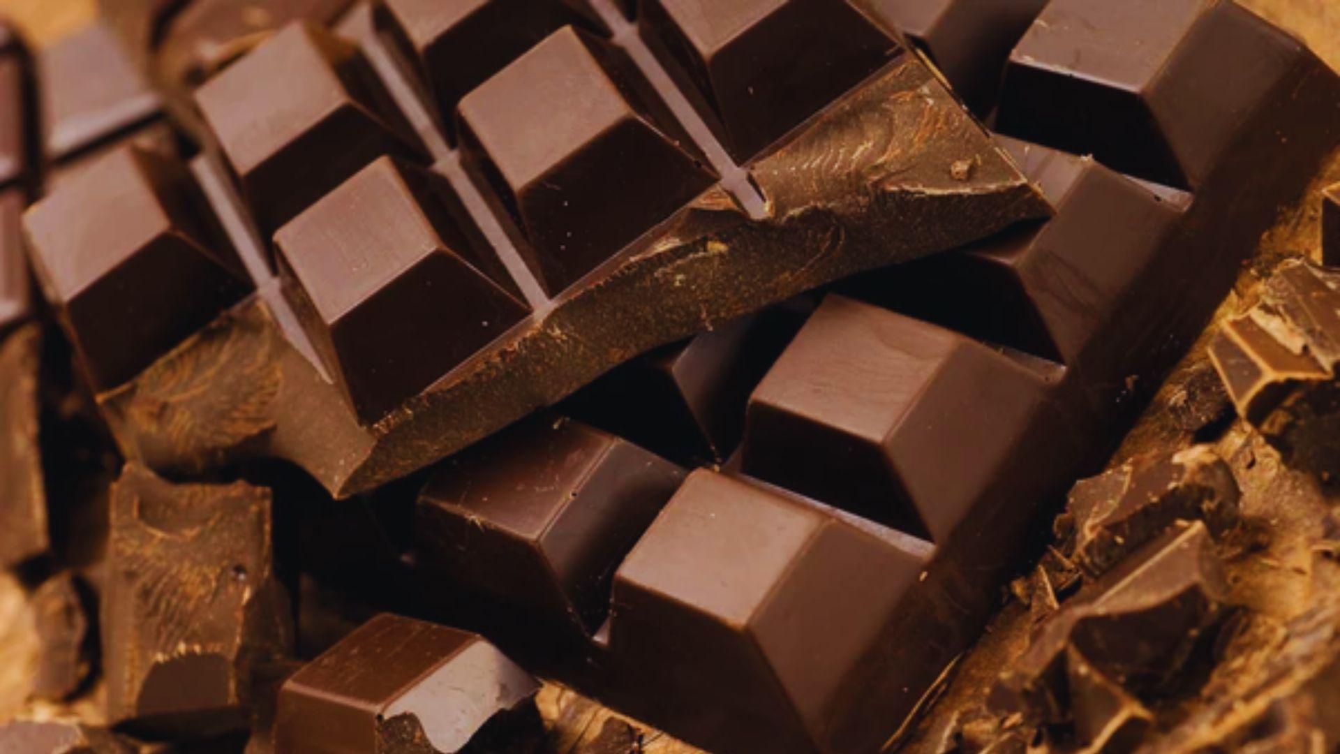 Close-up of dark chocolate bars with rich, glossy squares and textured edges. The image conveys indulgence and luxury, emphasizing rich details.