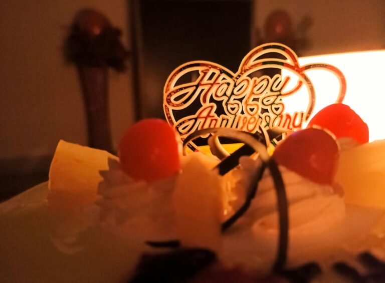 A decorated cake featuring a lit candle placed in an elegant candle holder on top.