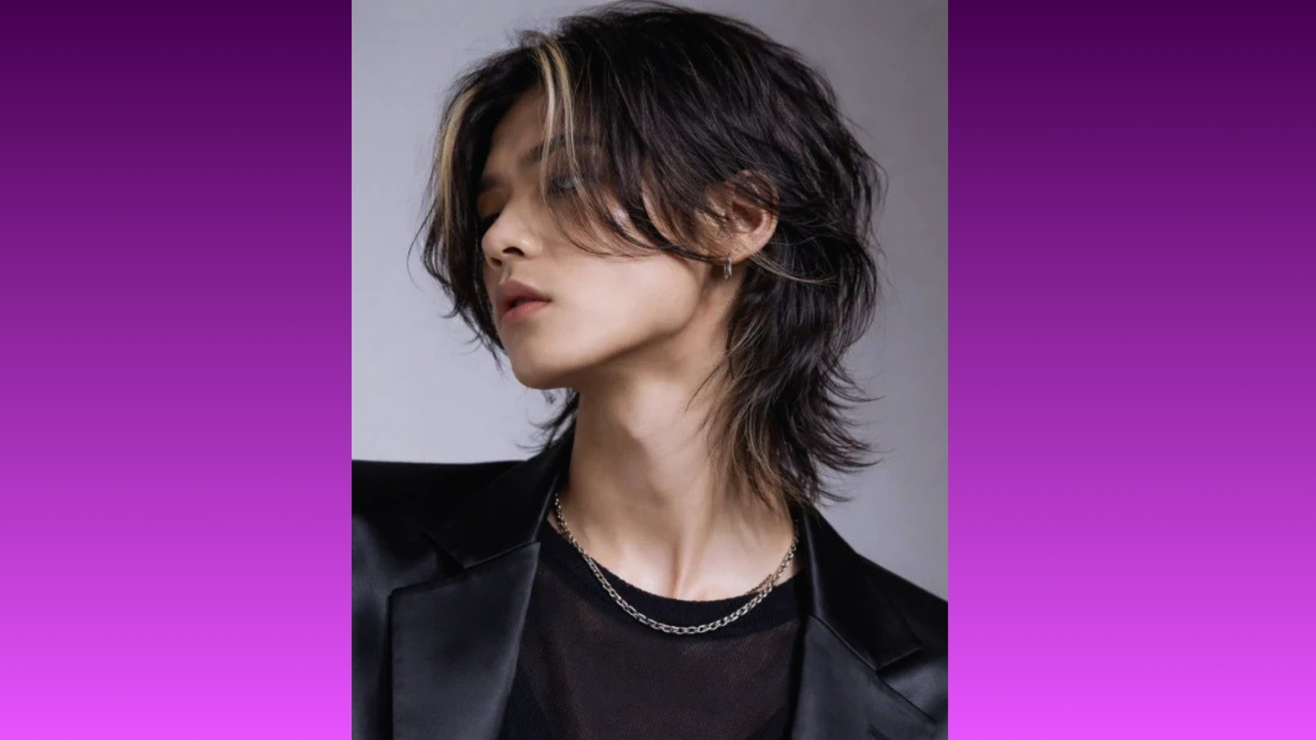 Person with layered shoulder-length hair, side gaze, wearing a black outfit and silver chain necklace. The background is a gradient of purple hues.