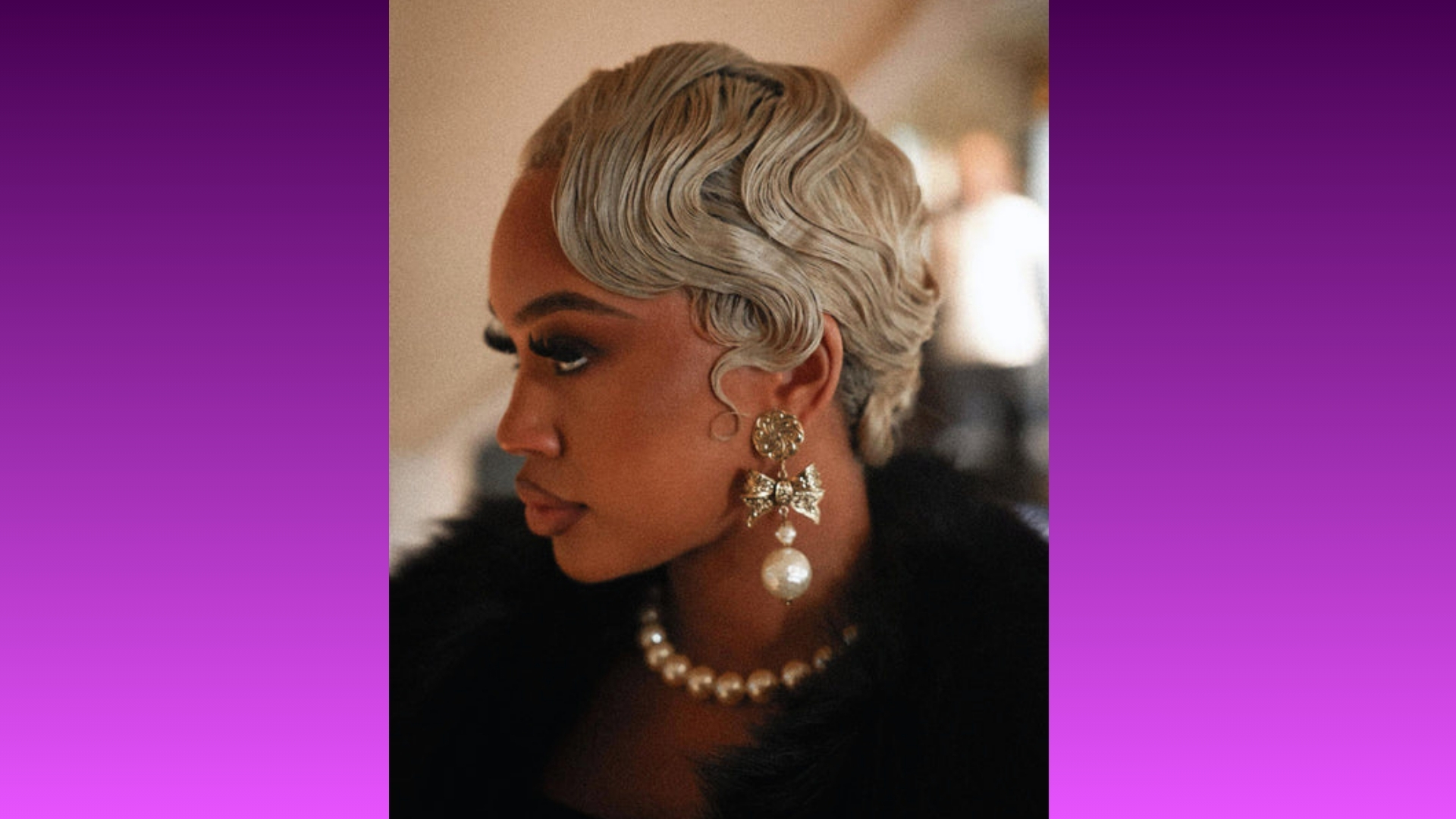 Woman with elegant platinum finger waves hairstyle and bold makeup, wearing intricate pearl earrings and necklace, against a soft gradient background.