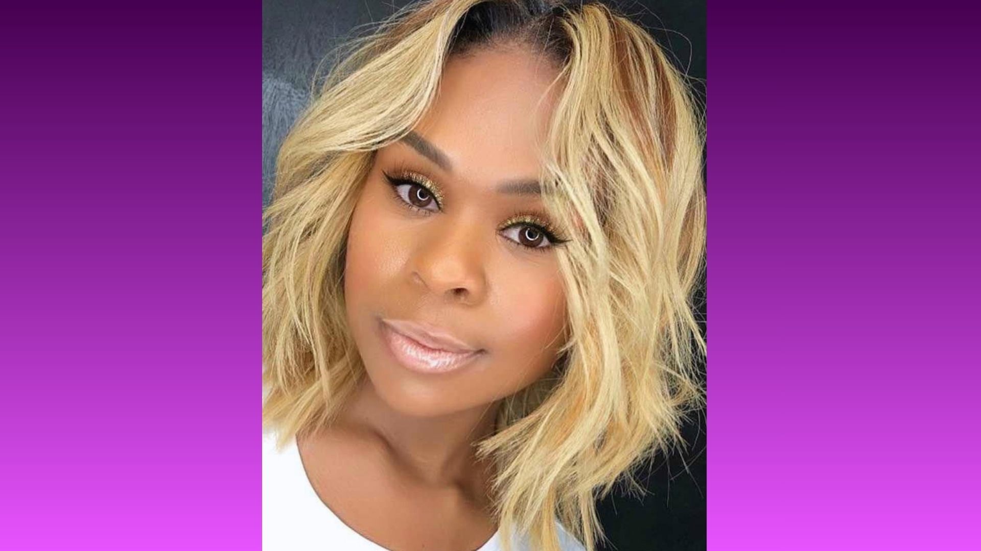 A woman with wavy blonde hair smiles softly. Her makeup is subtle, with natural tones. The background fades from deep purple to pink, creating a warm, inviting atmosphere.