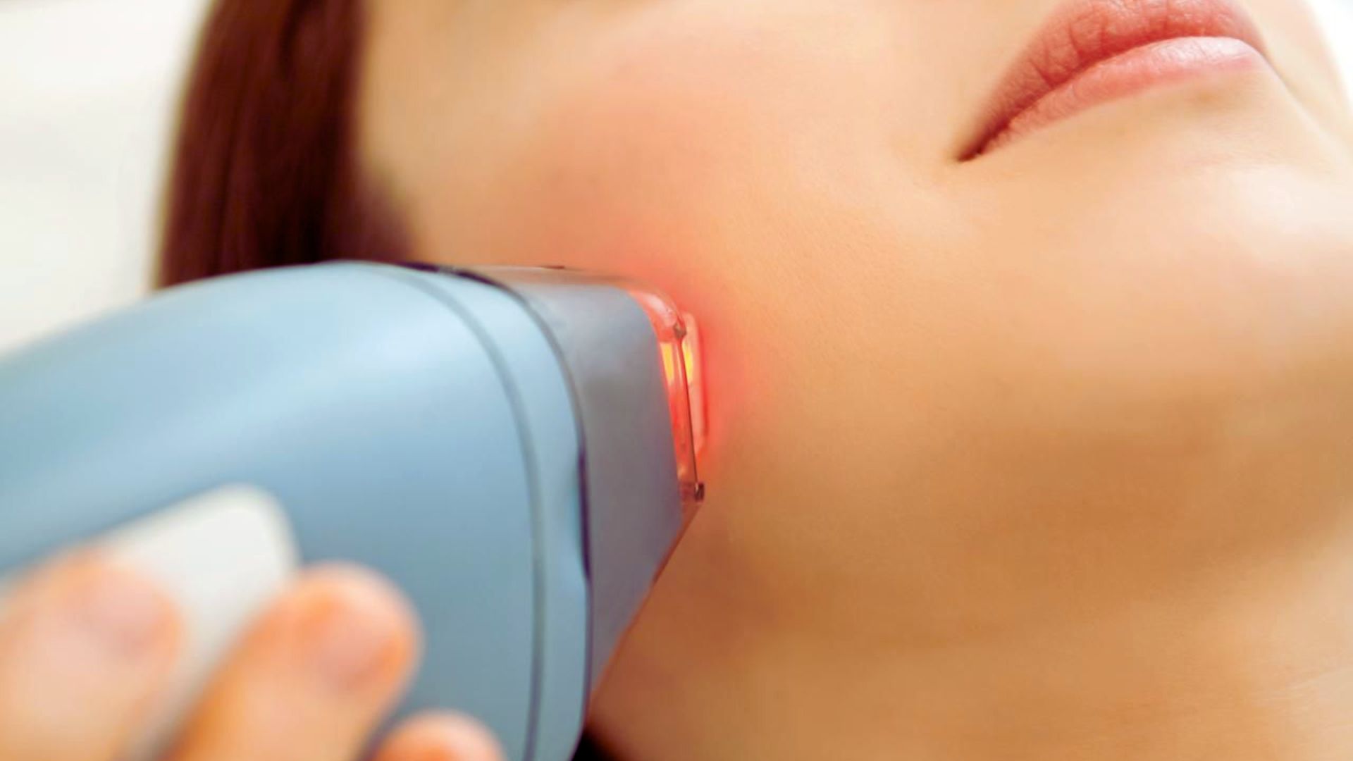 A woman applies an electric skin treatment device to her face, focusing on skincare and rejuvenation.