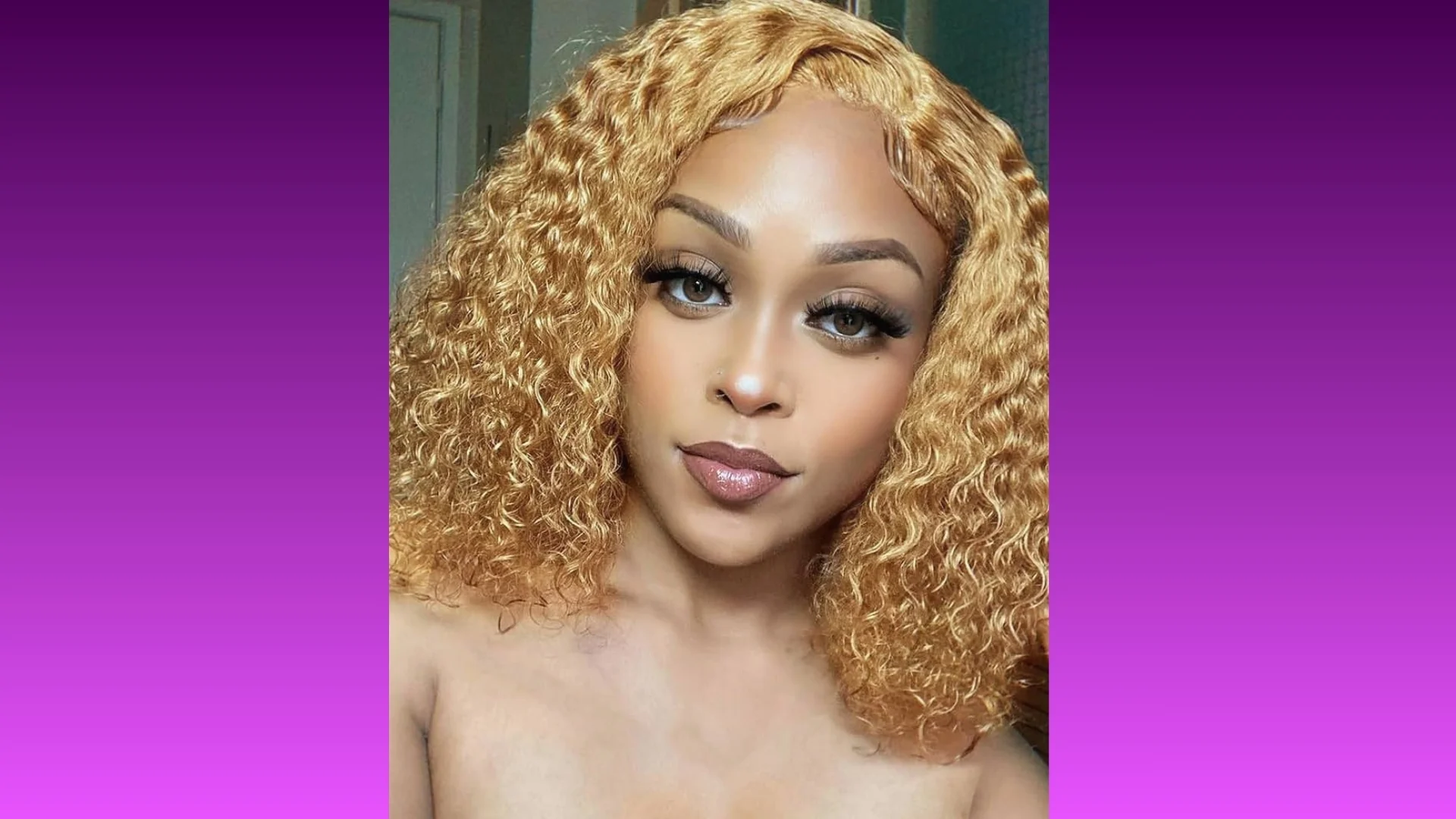 Young woman with curly, golden hair poses against a purple gradient background, wearing natural makeup with long lashes, exuding a confident expression.