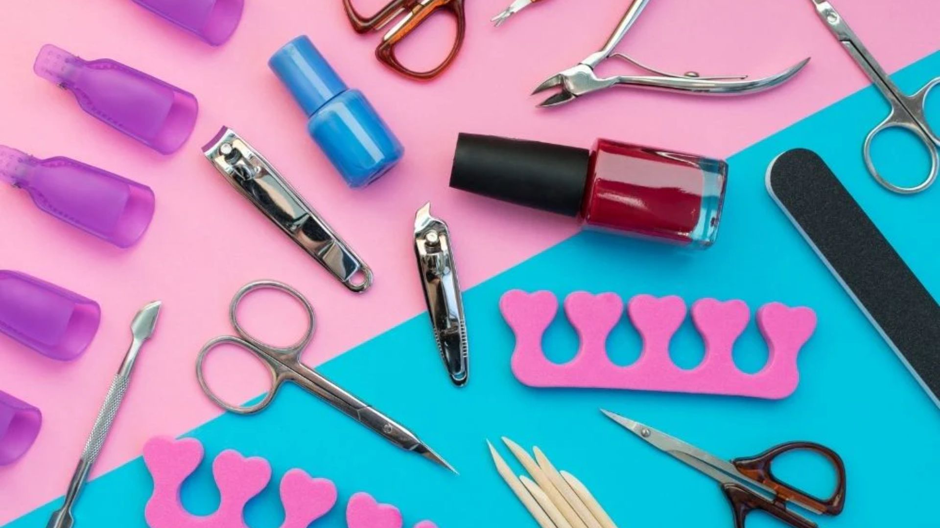 A flat lay of nail care tools on a split pink and blue background. Includes nail polish, clippers, scissors, and toe separators, conveying a colorful, organized aesthetic.