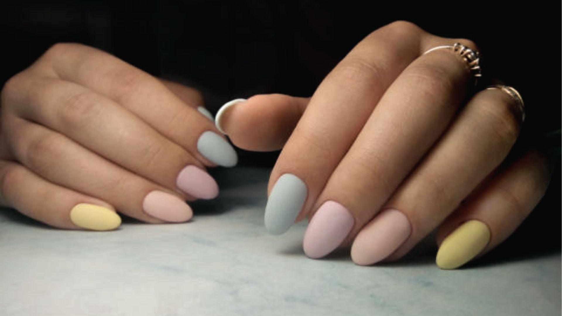 Short almond dip nails in matte pastel rainbow shades of yellow, peach, pink and blue on both hands.