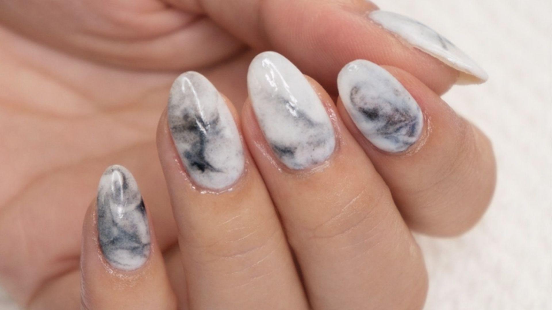Oval dip nails with glossy white marble effect and soft grey-black veining for a chic stone look.