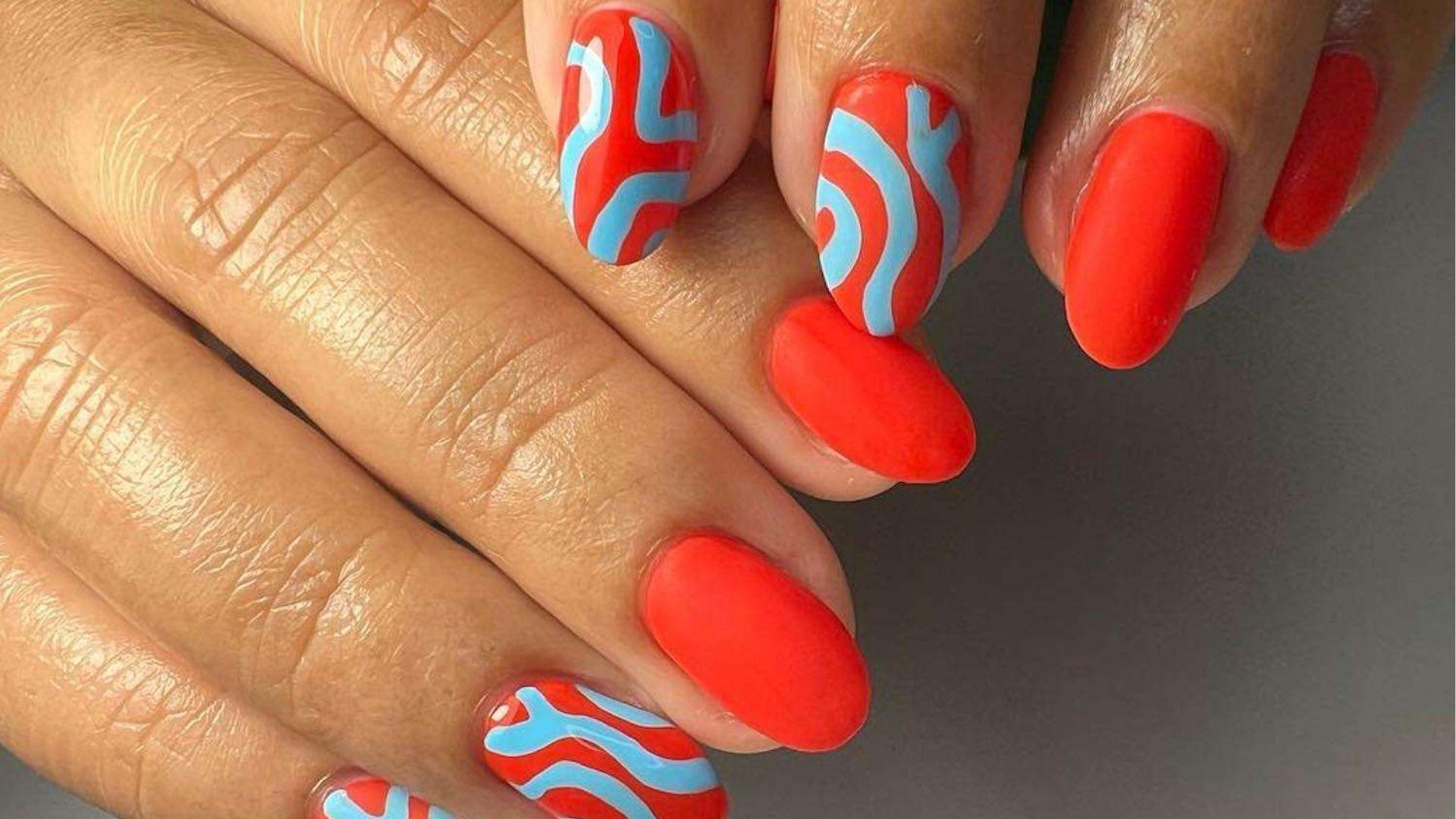 Almond dip nails in matte red with sky blue abstract swirl art on accent nails for a retro vibe.