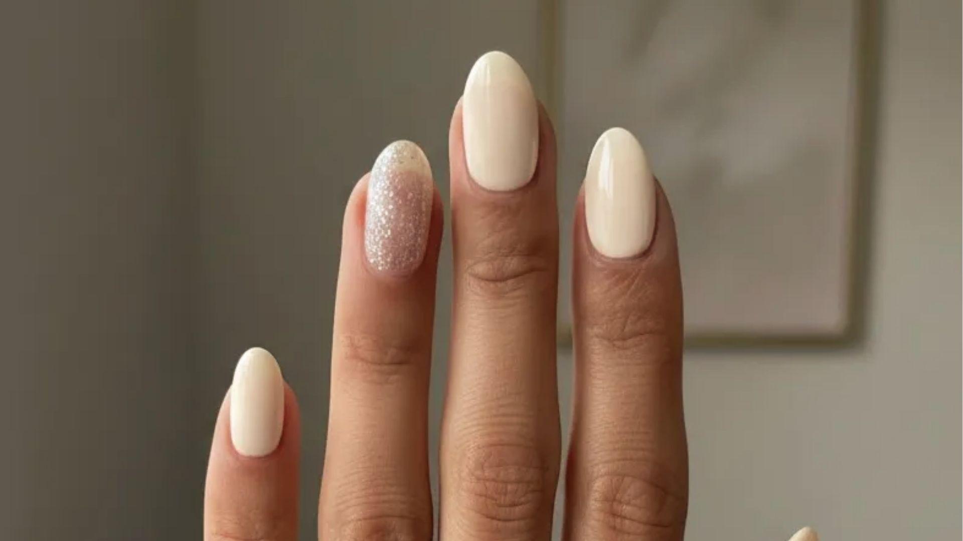 Short oval dip nails in glossy milky white with silver glitter accent nail for a soft bridal look.