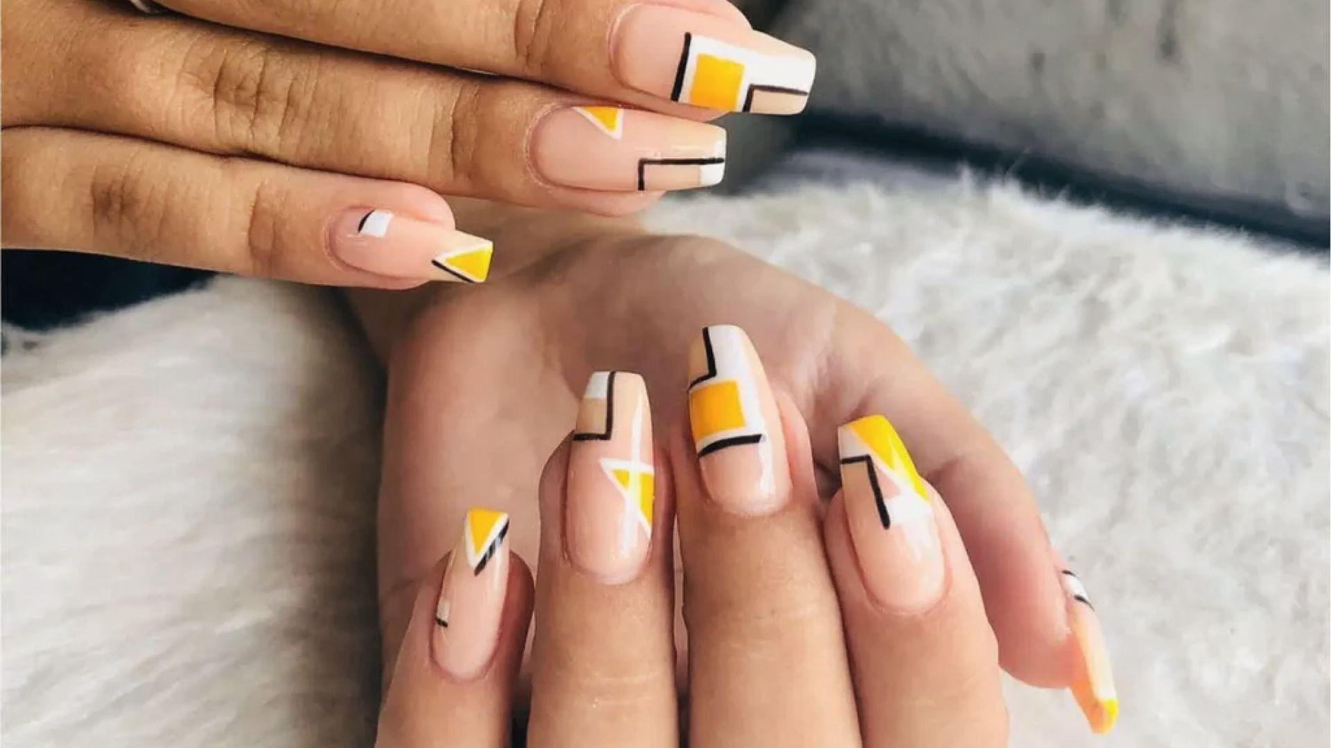 Short square dip nails in nude base with yellow, white, and black geometric art for a modern look.