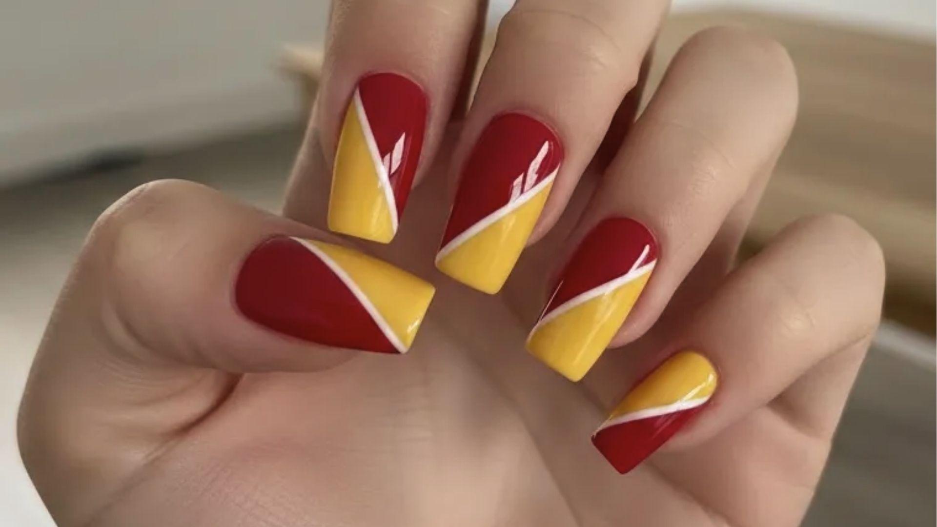 Short square dip nails with bold red and yellow diagonal color blocks split by thin white lines.