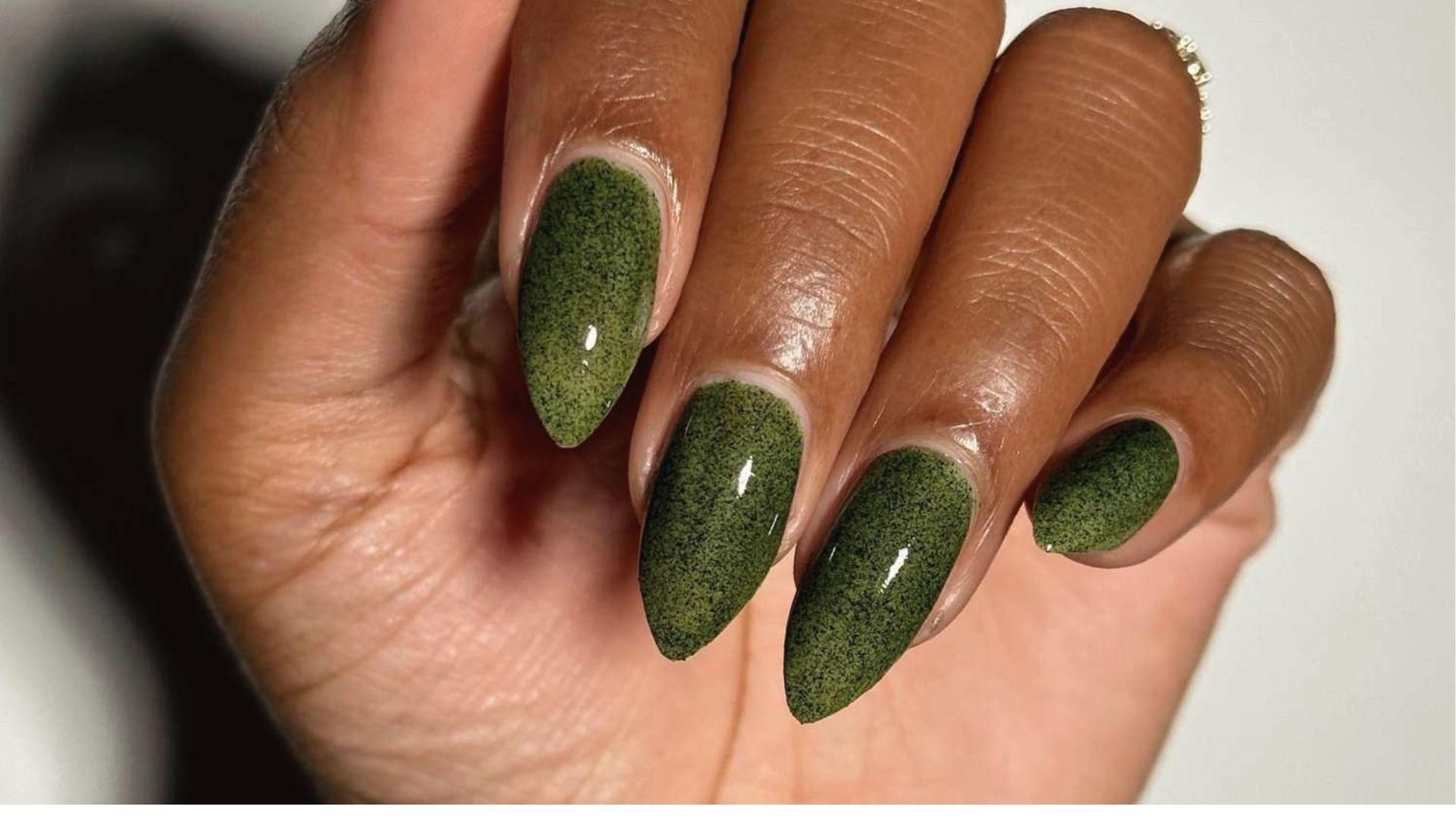 Almond dip nails in glossy olive green with fine black speckles for a textured moss or granite effect.