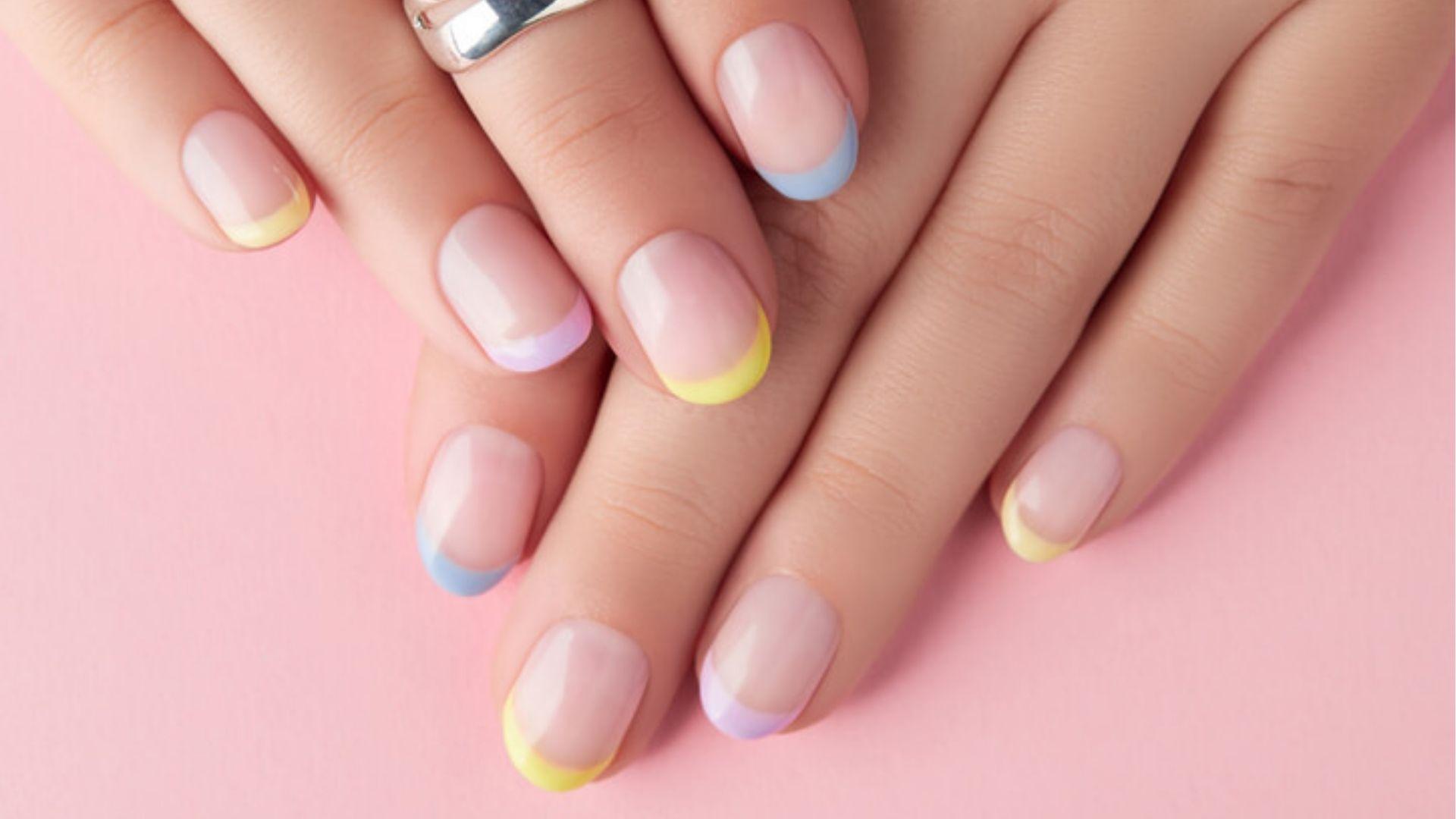 Pastel French tip gel nails on pink background, gel polish typically lasts 2-3 weeks intact.
