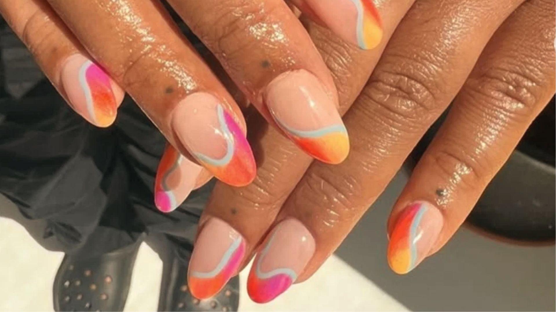 Almond dip nails with nude base and abstract sunset tips in pink, orange, yellow with blue outlines.